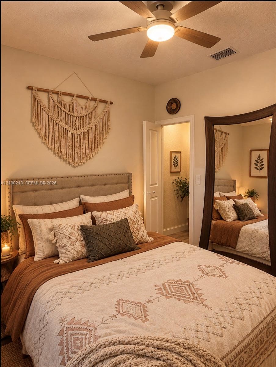Neutral-toned room featuring a five-blade ceiling fan with integrated lighting and a tufted upholstered headboard with nailhead trim