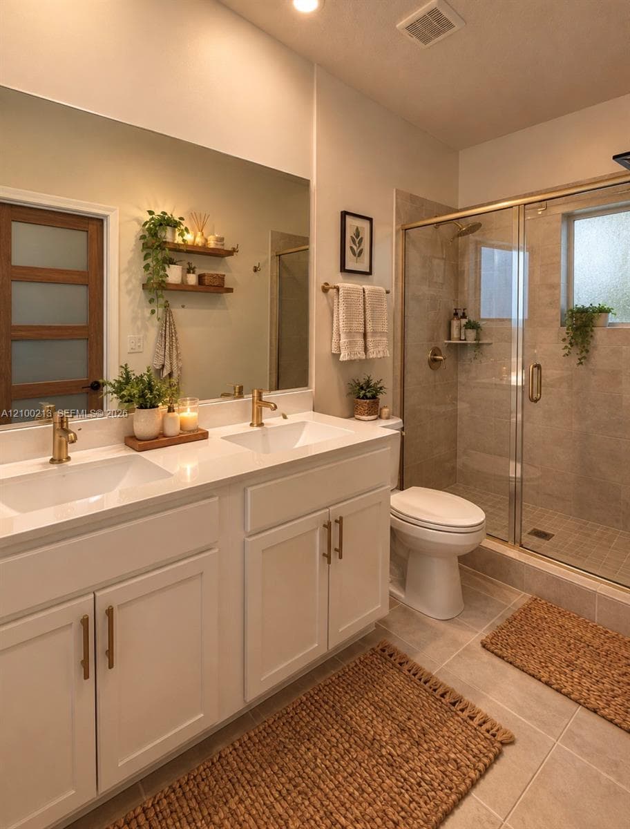 Double vanity with white cabinetry, rectangular under-mount sinks, and metallic gold-finish fixtures topped with light-toned solid surface counters