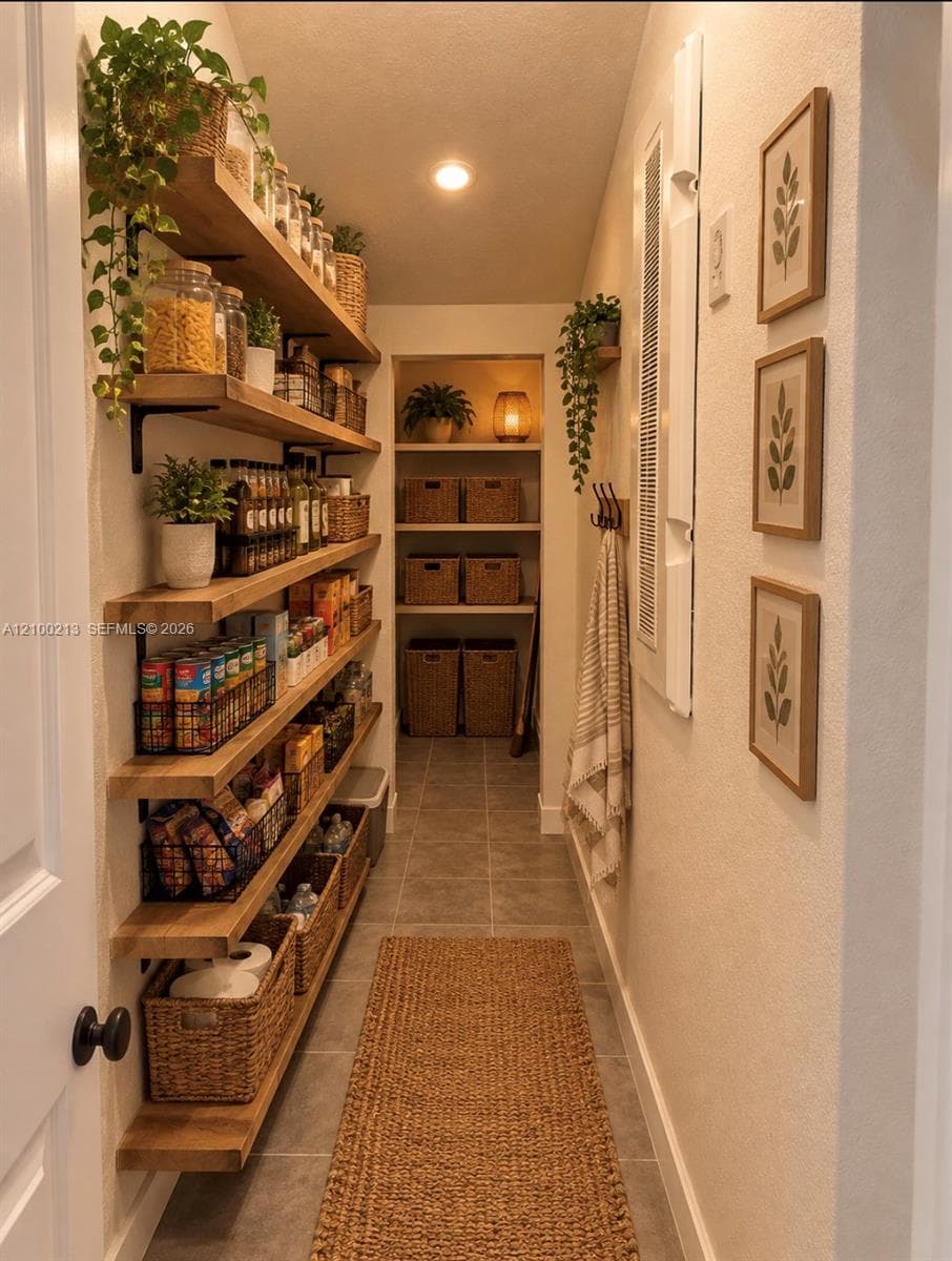 Pantry featuring multi-level natural wood shelving, tile flooring, and integrated wall-mounted storage hooks