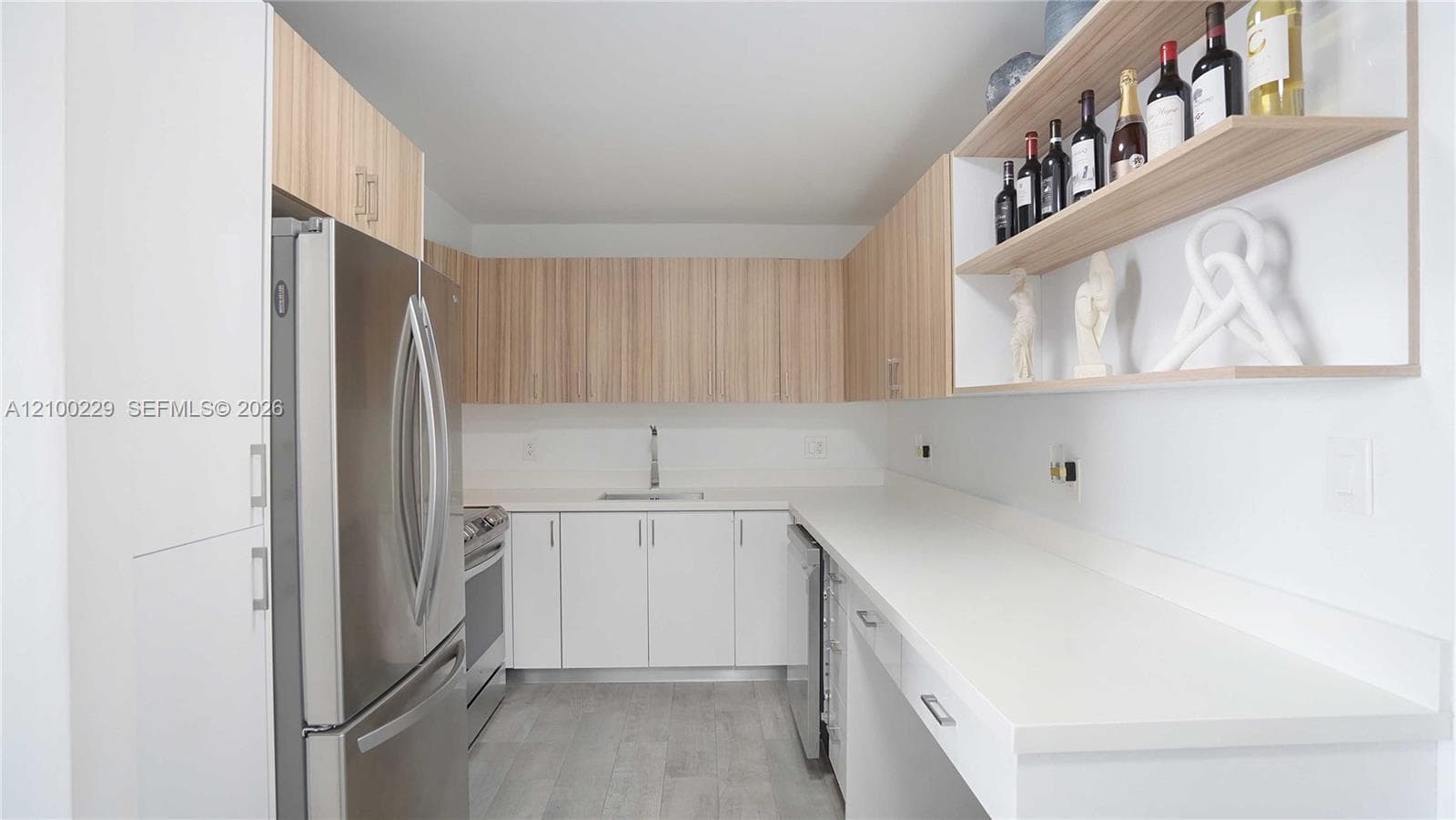 Kitchen featuring wood-finish cabinetry, stainless steel appliances, solid surface countertops, built-in open shelving, and neutral wood-finish flooring