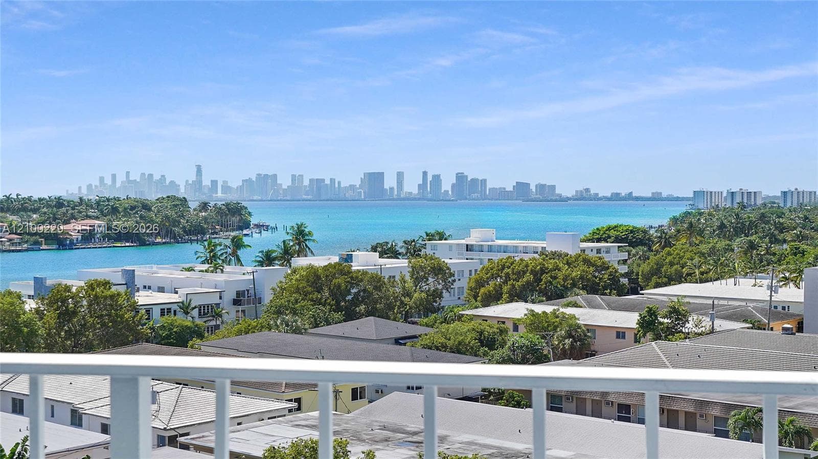 Elevated balcony featuring a white metal railing, showcasing a panorama of the coastal waterway and the distant city skyline