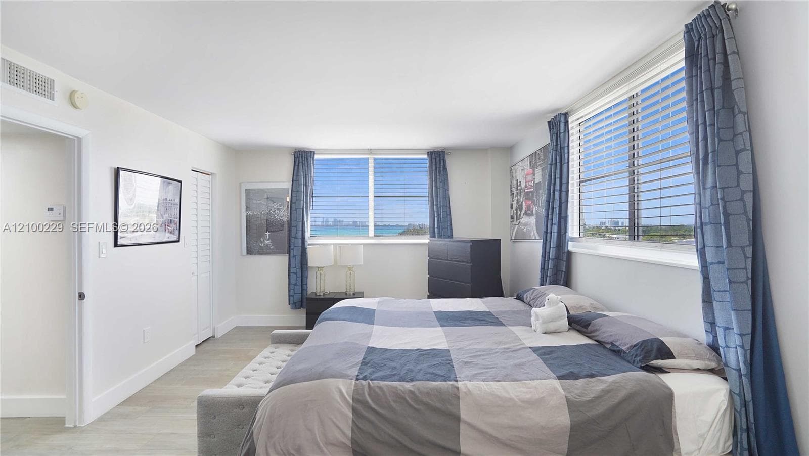 Neutral-toned interior space featuring light-toned flooring, multi-pane windows, and water-inclusive horizon scenery