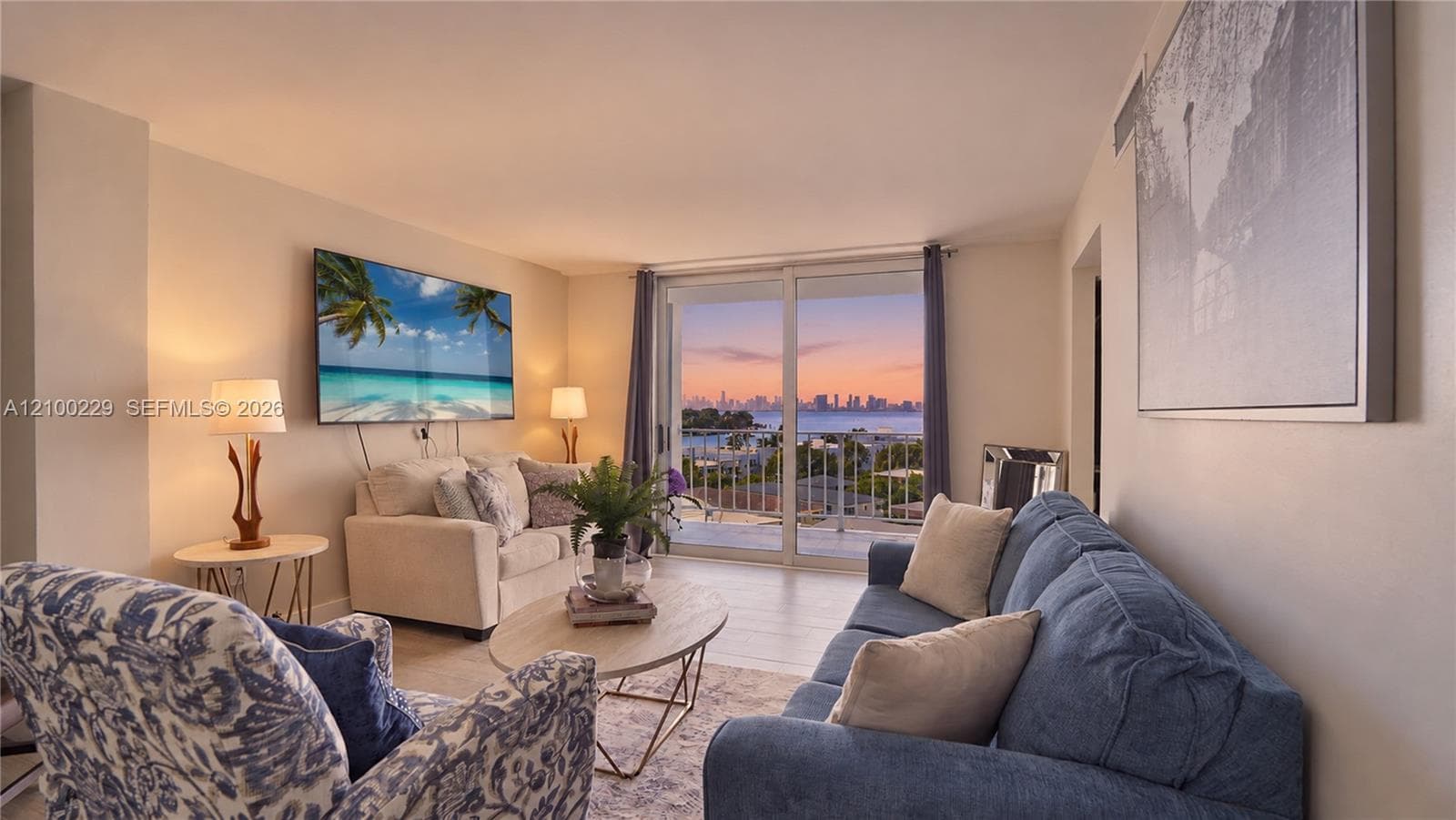 Living area featuring wood-finish flooring, floor-to-ceiling glass sliding doors, and a balcony with an expansive cityscape and water horizon