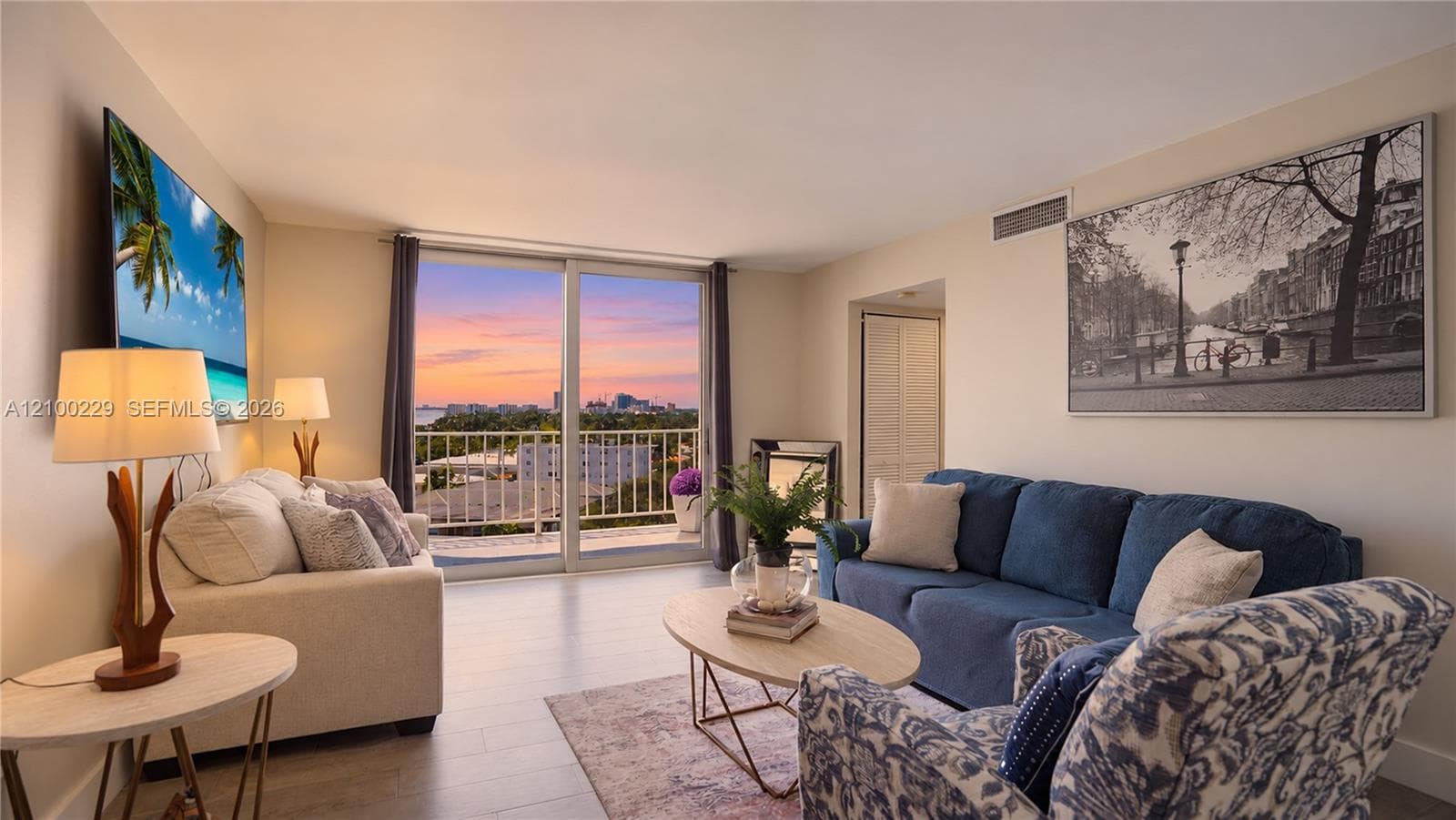 Floor-to-ceiling sliding glass doors, private balcony, wood-finish flooring, and expansive horizon backdrop