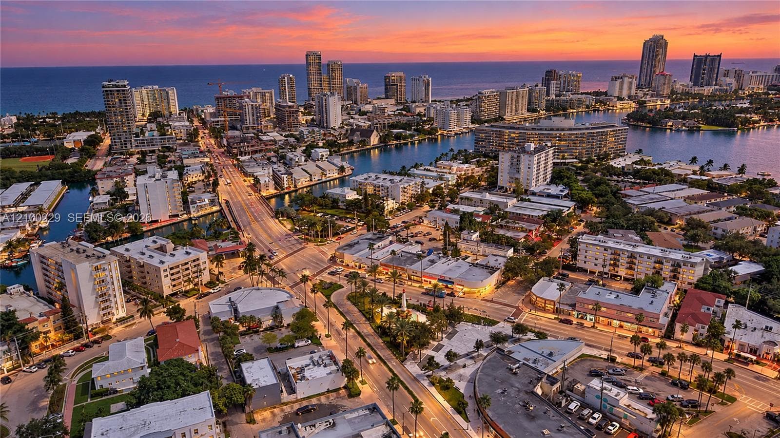 Aerial perspective of an urban coastal district featuring waterways, high-rise residential buildings, and prominent ocean horizon