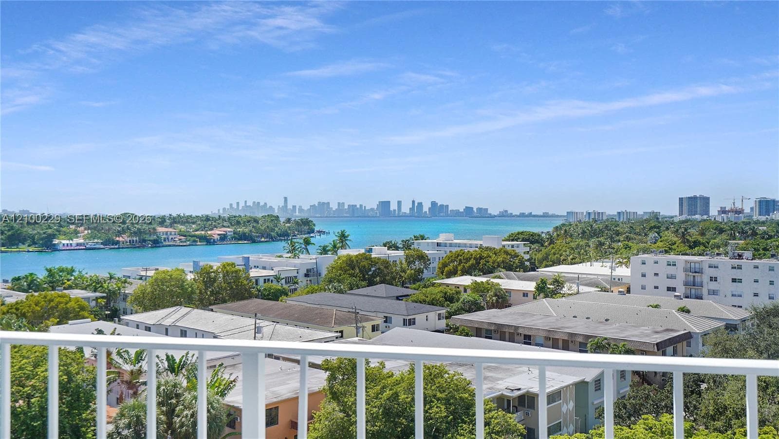 Elevated balcony featuring a white metal railing and an expansive panorama of the waterway and city skyline