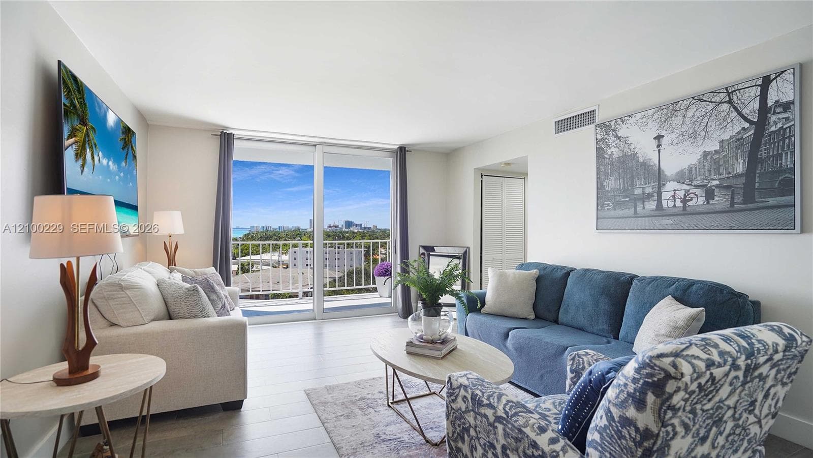 Living area featuring light-toned wood-finish flooring, floor-to-ceiling glass sliding doors, and a private balcony