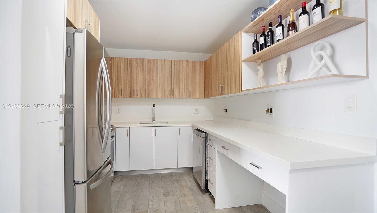 Kitchen featuring two-tone cabinetry with wood-finish upper cabinets, solid-surface countertops, built-in stainless steel appliances, open shelving, and wood-finish flooring