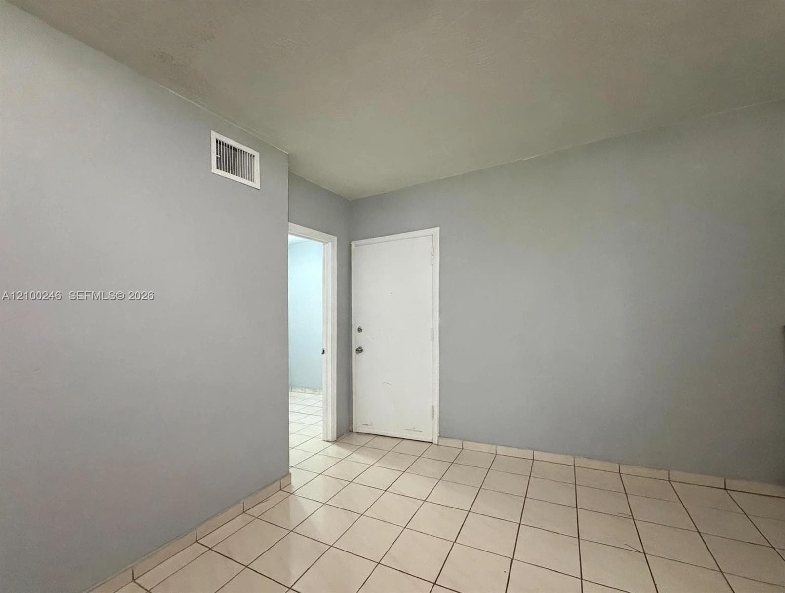 Neutral-toned interior walls, ceramic tile flooring, and a solid-core interior door