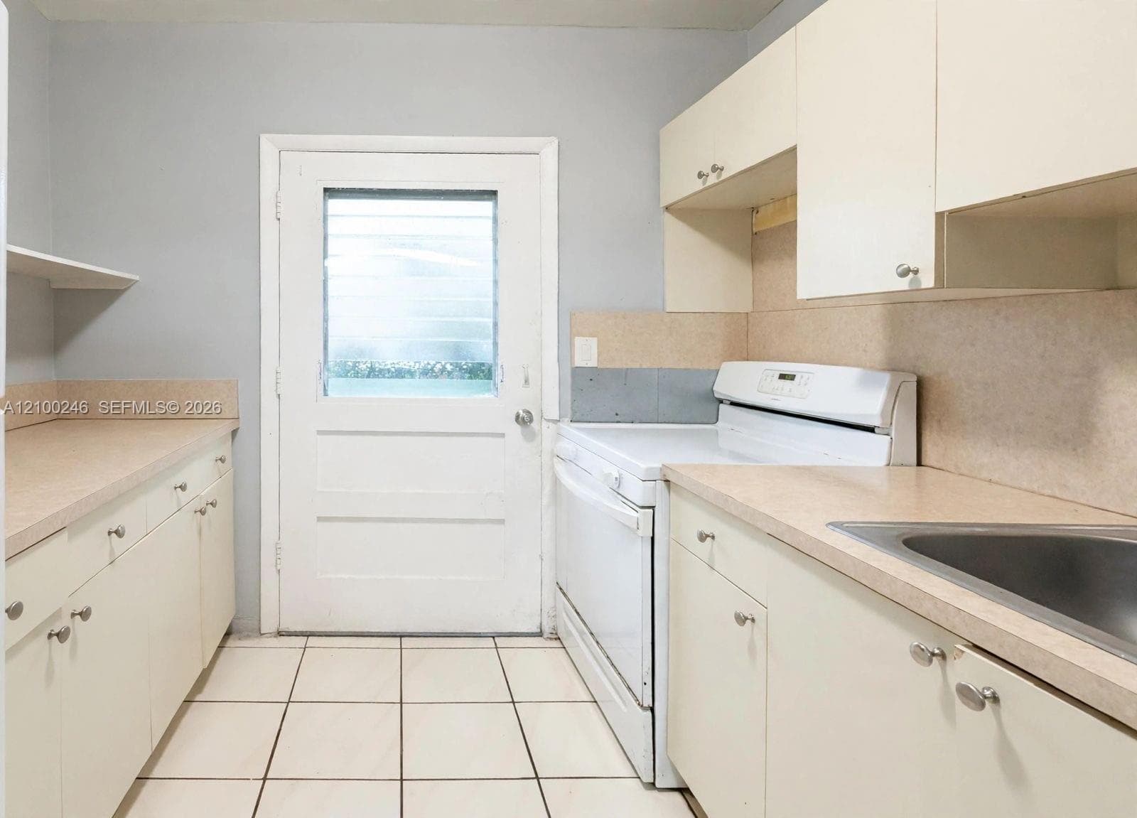 Kitchen featuring flat-panel cabinetry, solid-surface countertops, tile flooring, and an integrated range