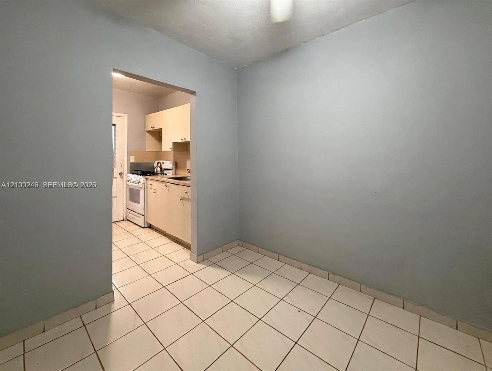 Ceramic tile flooring throughout, featuring light-toned cabinetry and a white freestanding gas range