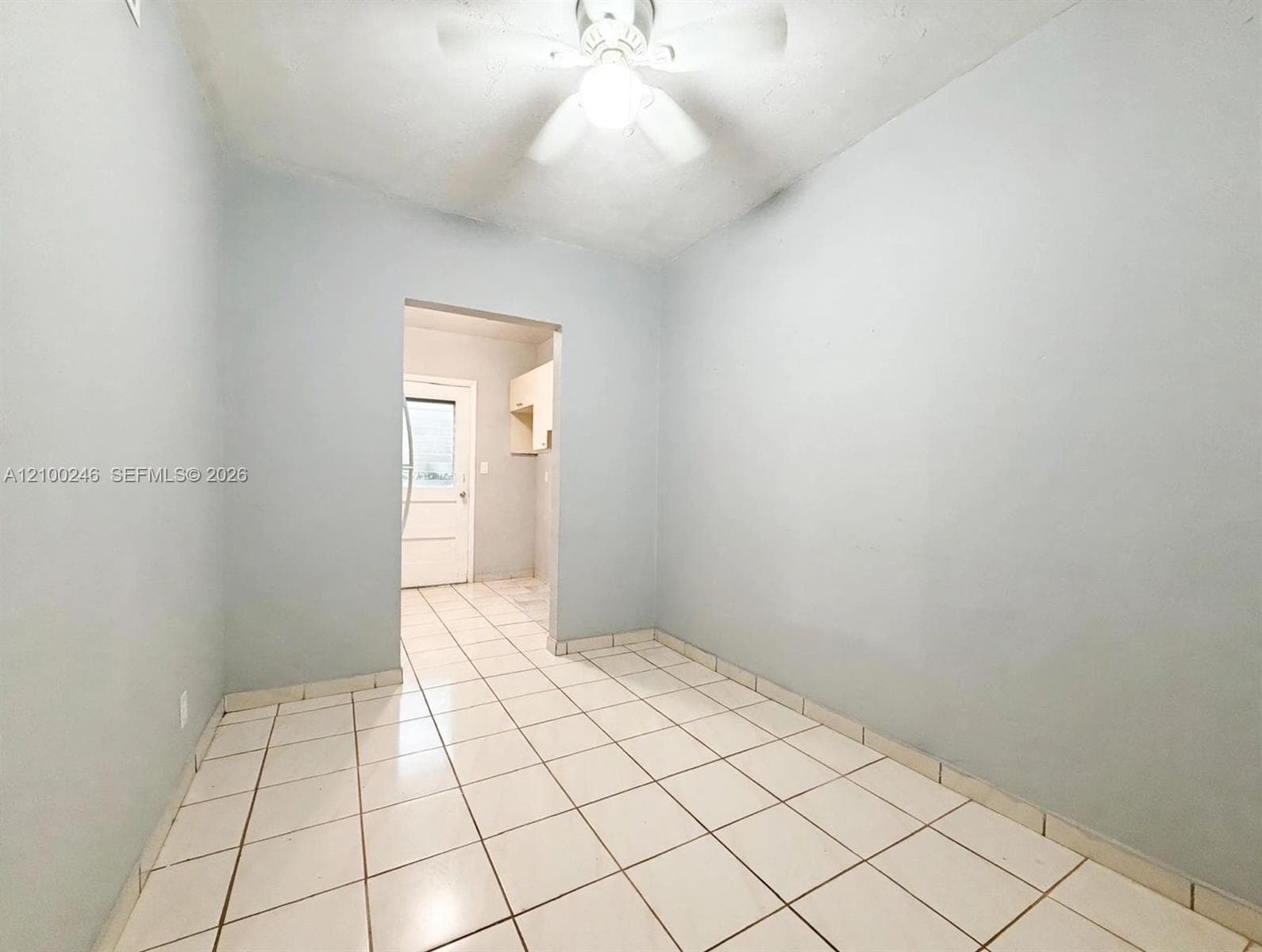 Interior room featuring light-colored tile flooring and a ceiling-mounted fan with integrated light fixture