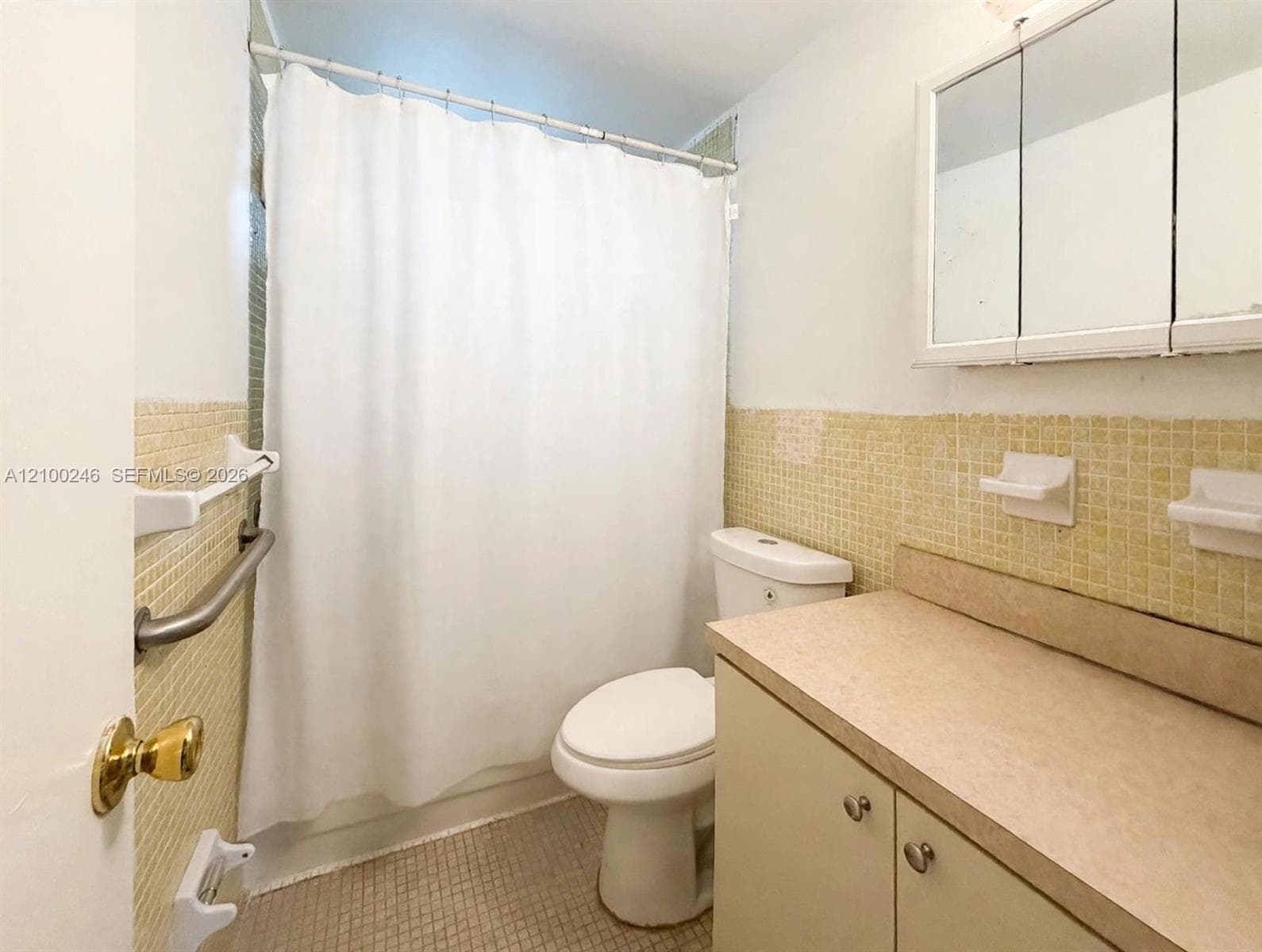 Bathroom featuring yellow square tile wall accents, a vanity with a solid-surface countertop, a mirrored medicine cabinet, and a wall-mounted grab bar