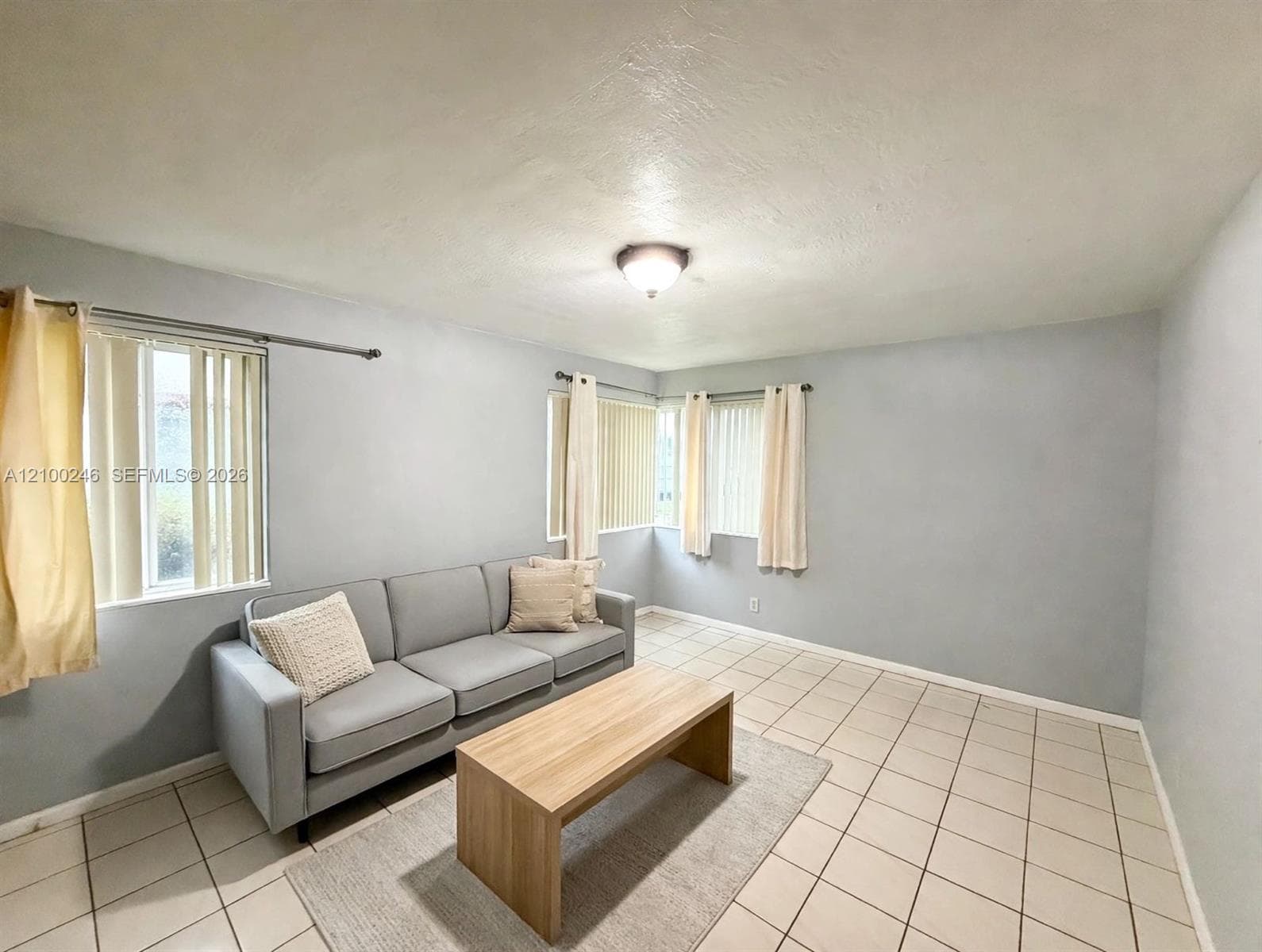 Ceramic tile flooring, neutral wall tones, and three windows with adjustable vertical blinds