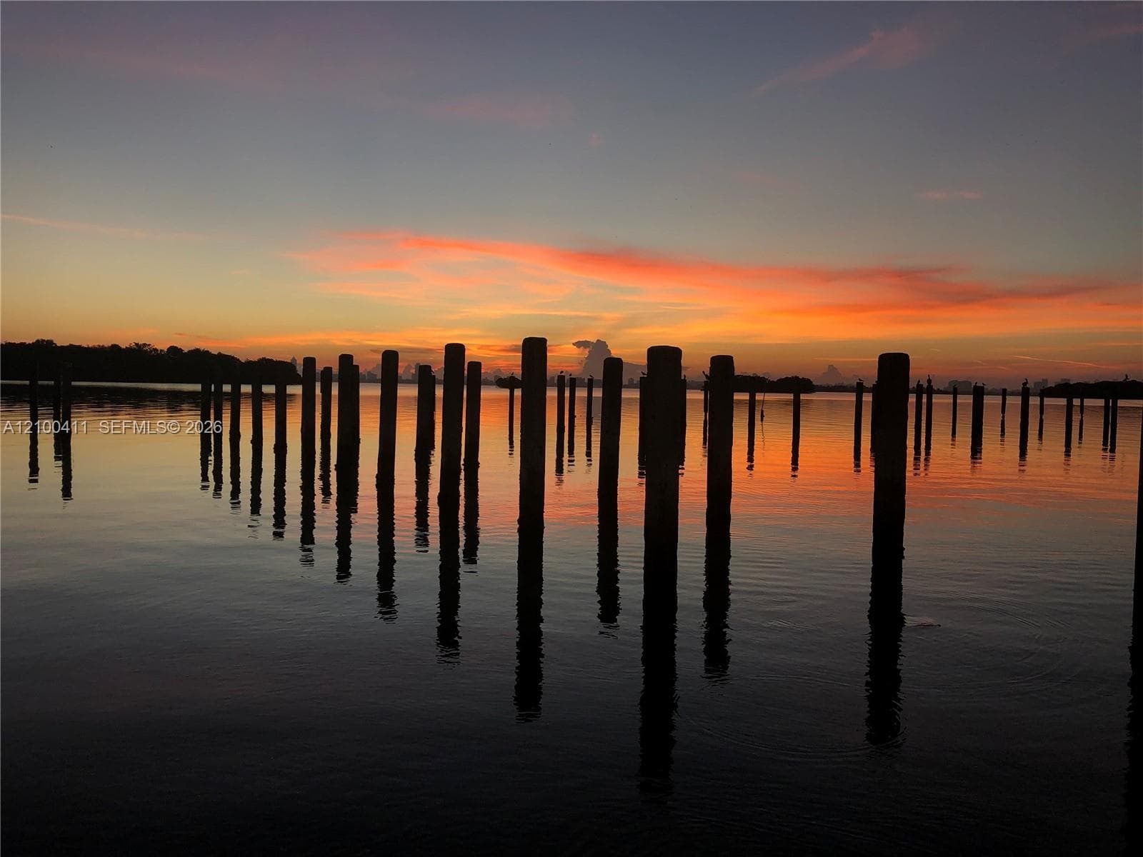 Waterfront bulkhead pilings set against a colorful sunset backdrop