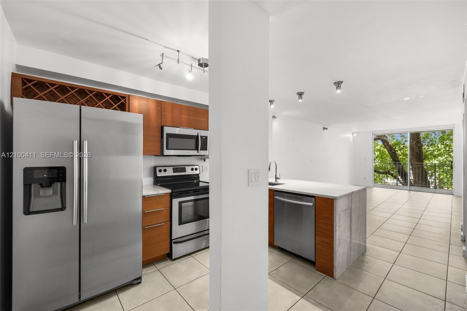 Kitchen featuring wood-finish cabinetry, stainless steel appliances, stone-surface countertops, a center island with integrated dishwasher, and tile flooring
