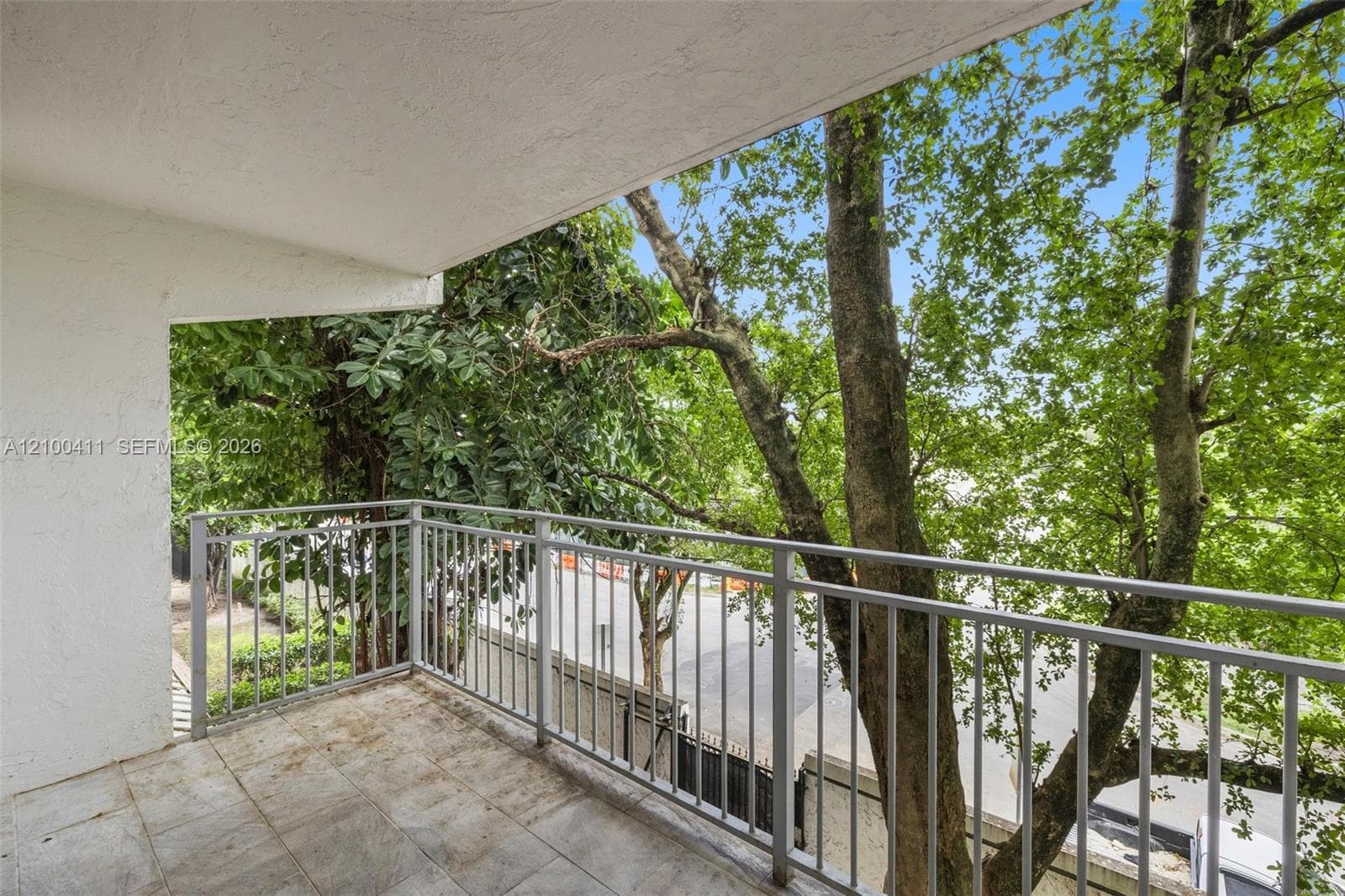 Private balcony featuring tiled flooring, a white textured ceiling, and a grey metal railing