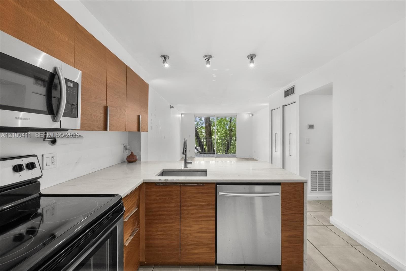 Kitchen featuring wood-finish cabinetry, solid surface countertops, stainless steel appliances, and recessed lighting