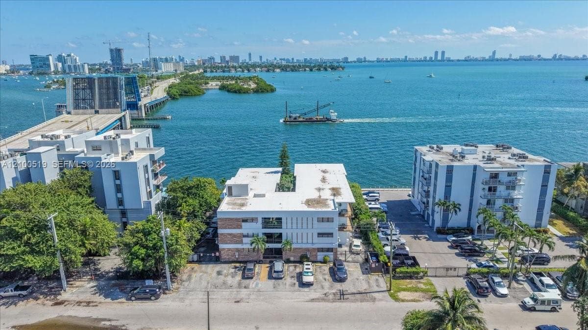 Aerial perspective of a multi-story residential complex featuring paved surface parking and waterfront proximity