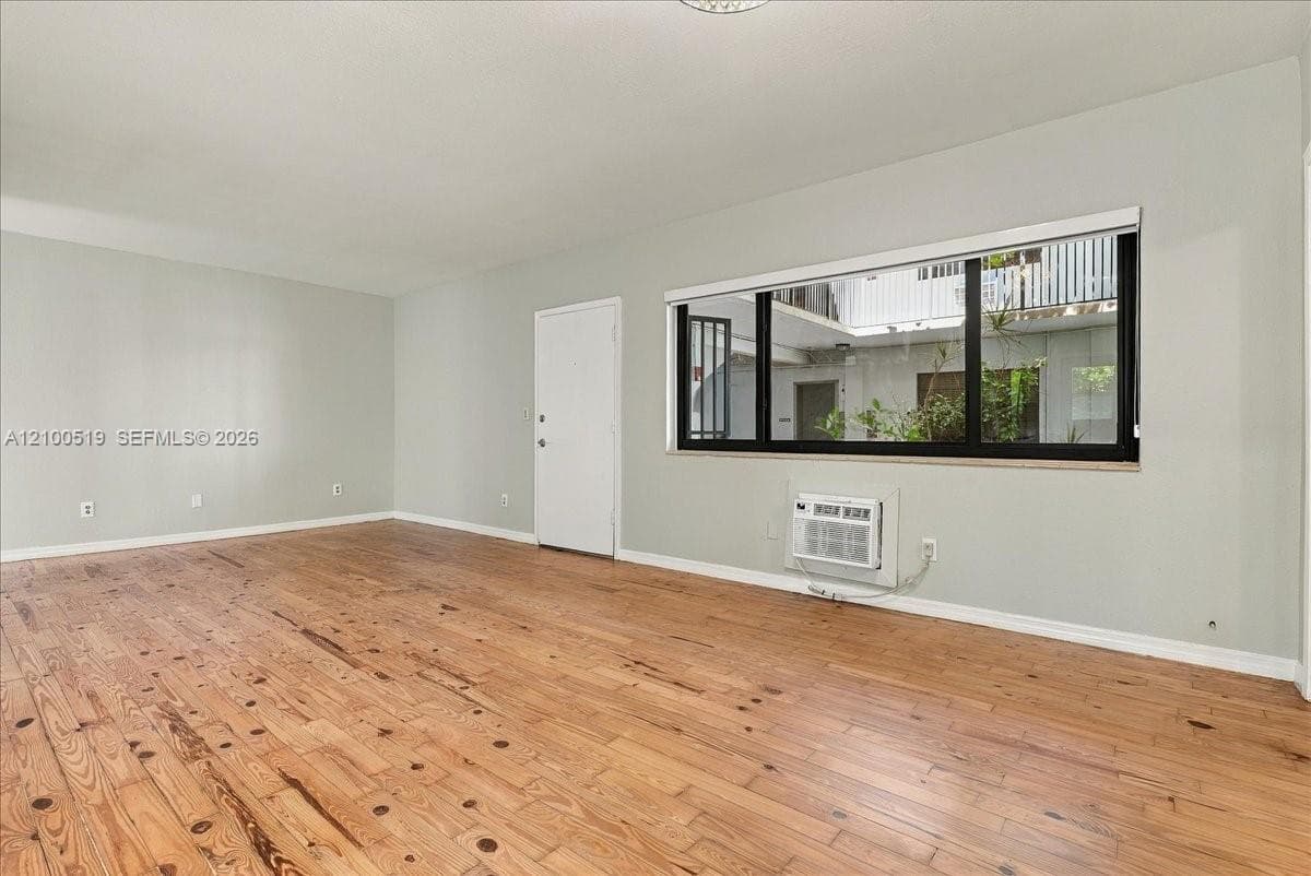 Interior space featuring wood-finish flooring, neutral wall paint, and a large window with black framing