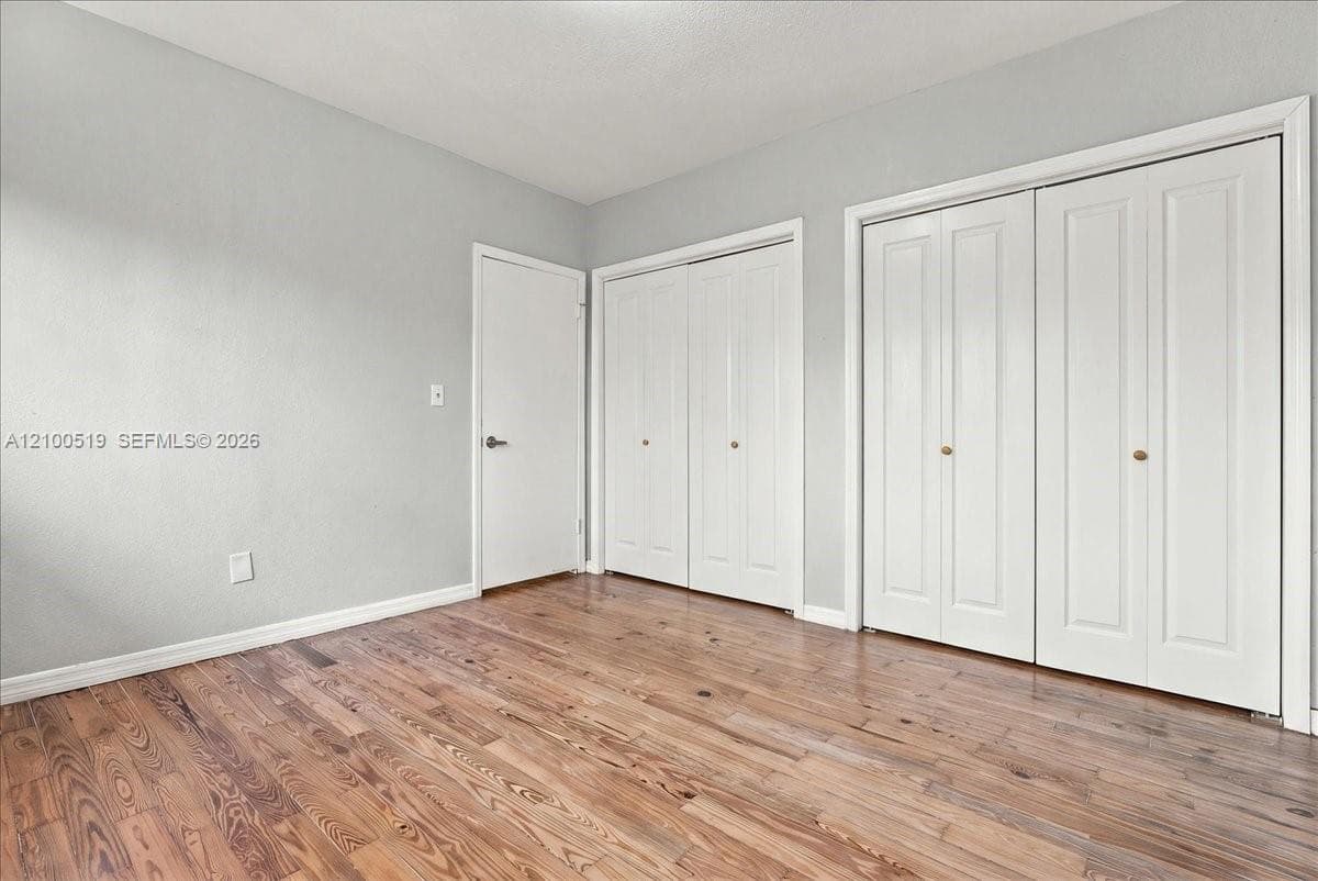 Wood-finish flooring featuring dual sets of white bi-fold closet doors and a single interior door
