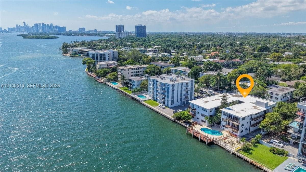 Waterfront property featuring a swimming pool, concrete seawall, and landscaped grounds