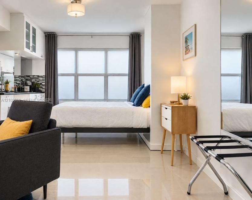 Large-format windows, polished neutral flooring, white cabinetry, mosaic tile backsplash, and full-length wall mirror