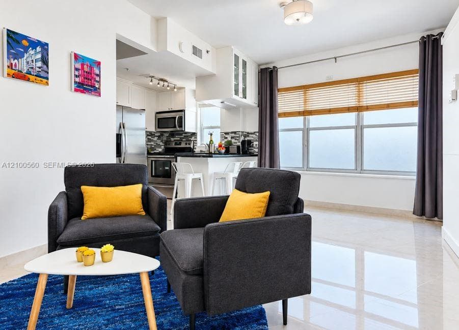 Open-concept kitchen featuring stainless steel appliances, dark countertops, glass-front cabinetry, and polished tile flooring