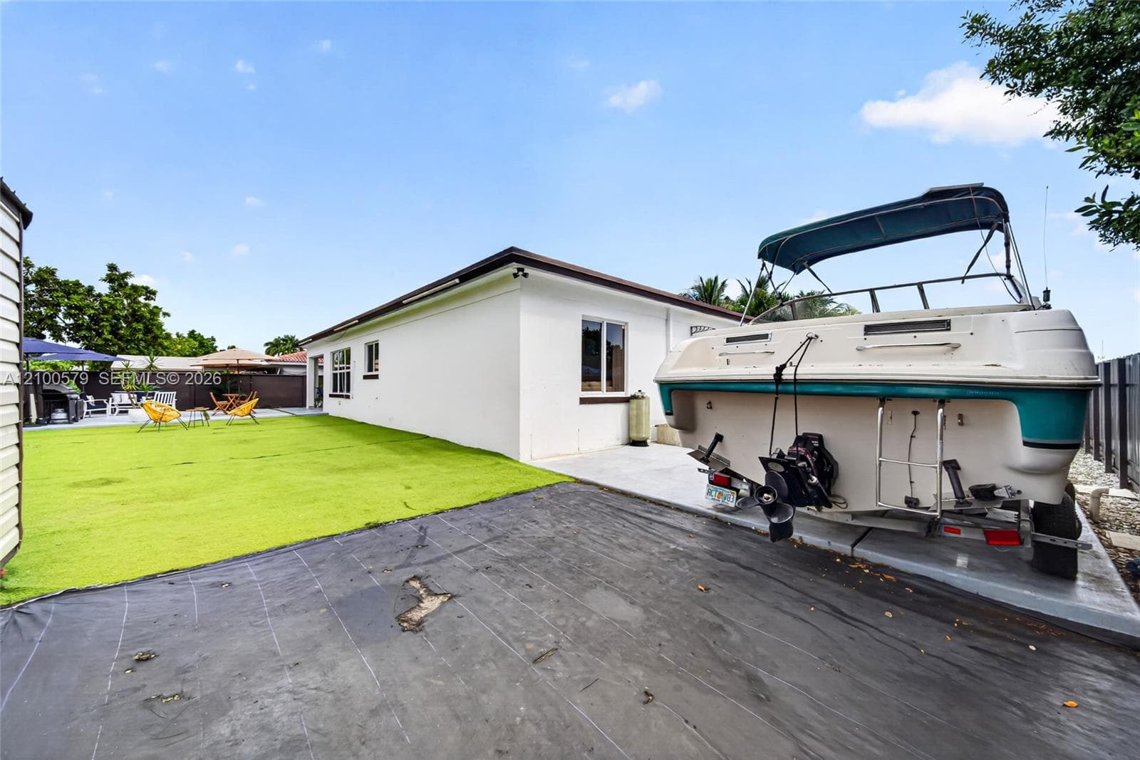 Rear exterior space featuring a white stucco facade, a concrete slab, and a green lawn area