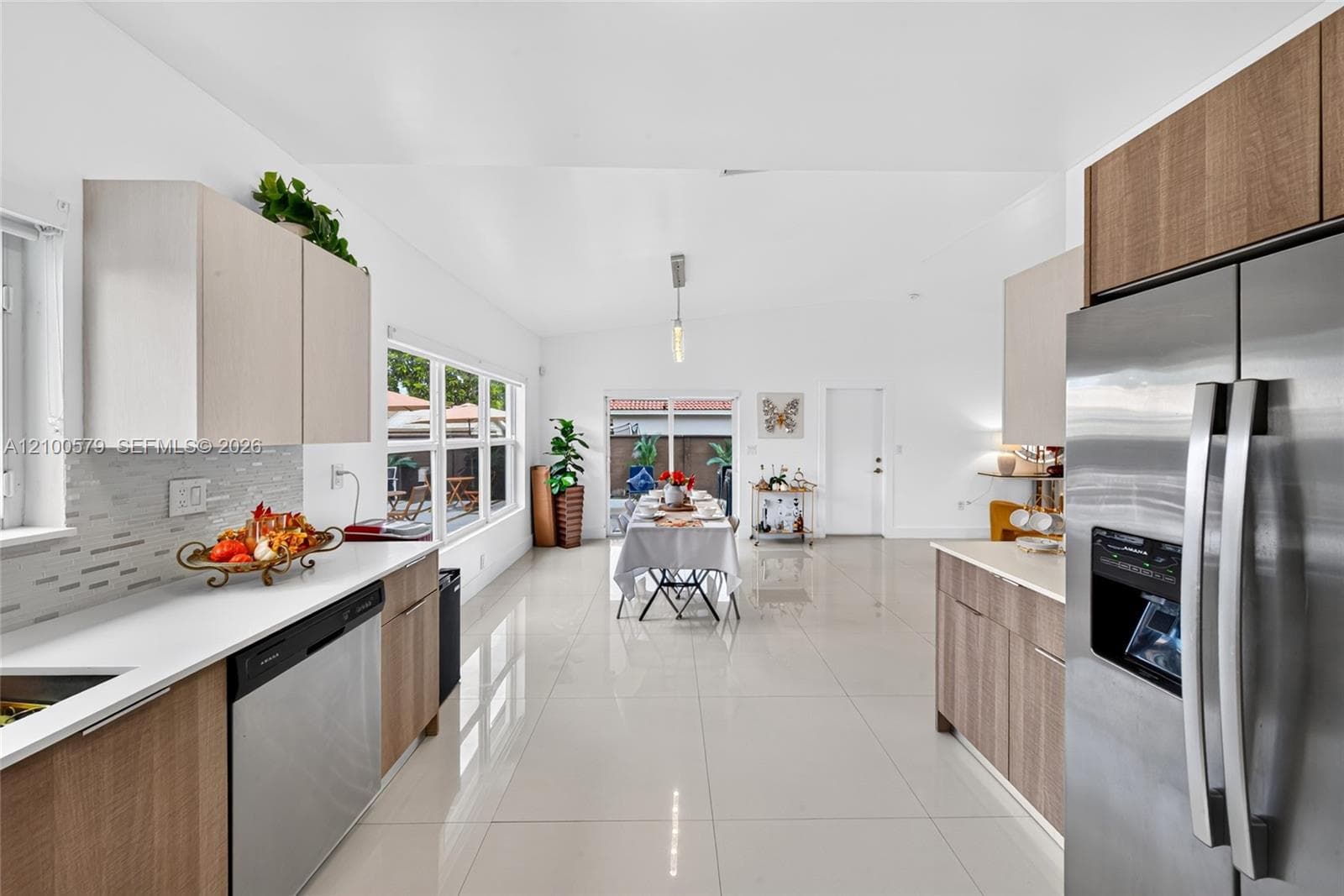 Kitchen featuring flat-panel wood-finish cabinetry, white countertops, stainless steel appliances, tile backsplash, and polished tile flooring
