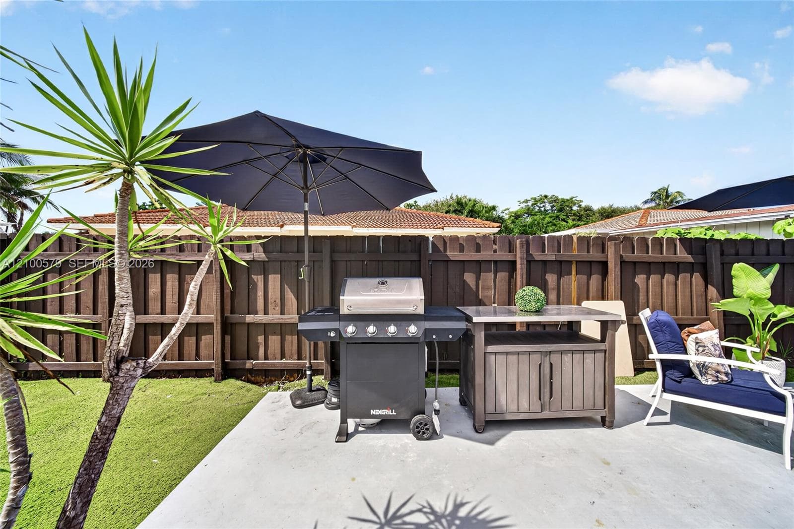 Outdoor patio featuring a poured concrete floor and a privacy wood fence