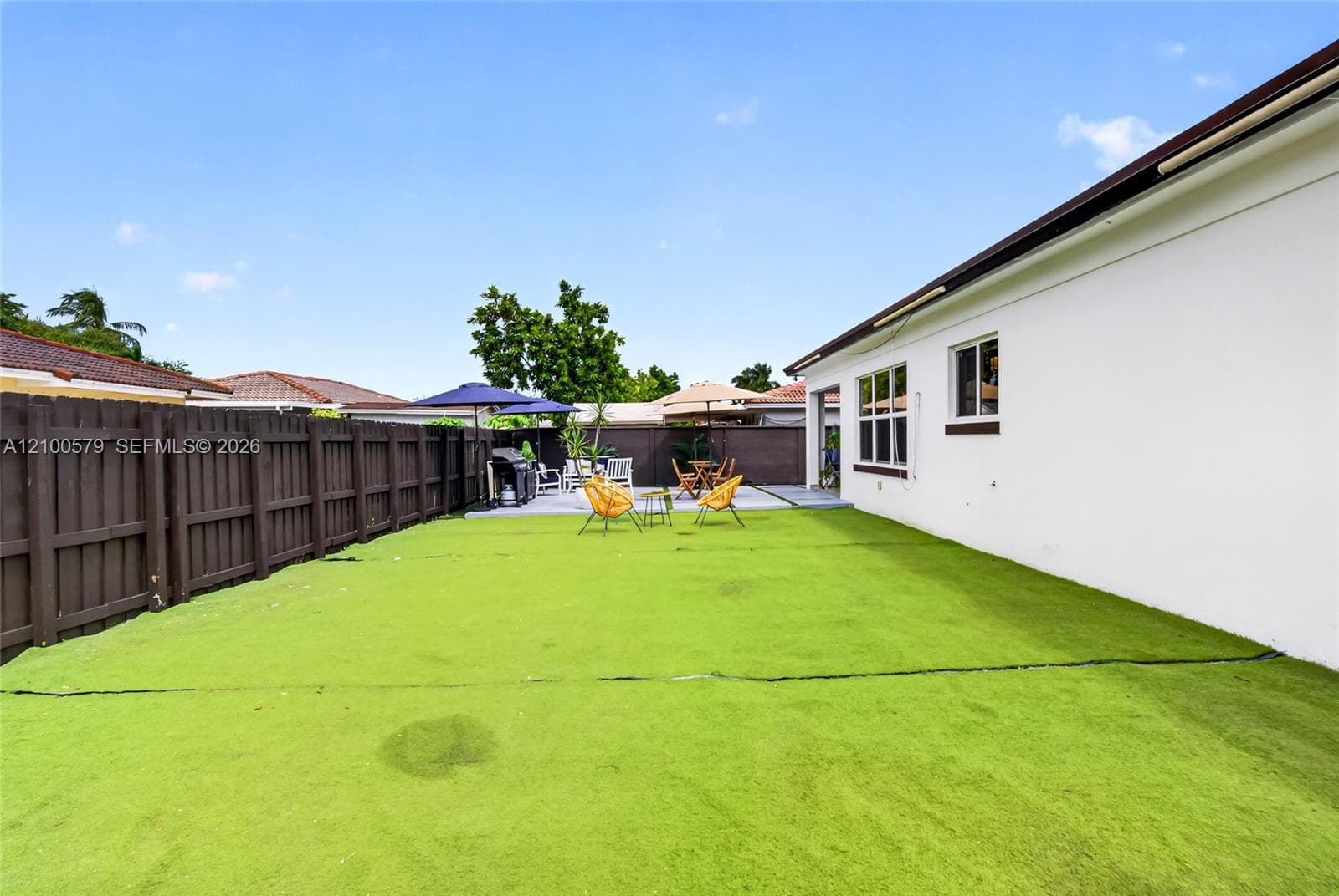 Fenced backyard featuring synthetic turf and a paved patio area