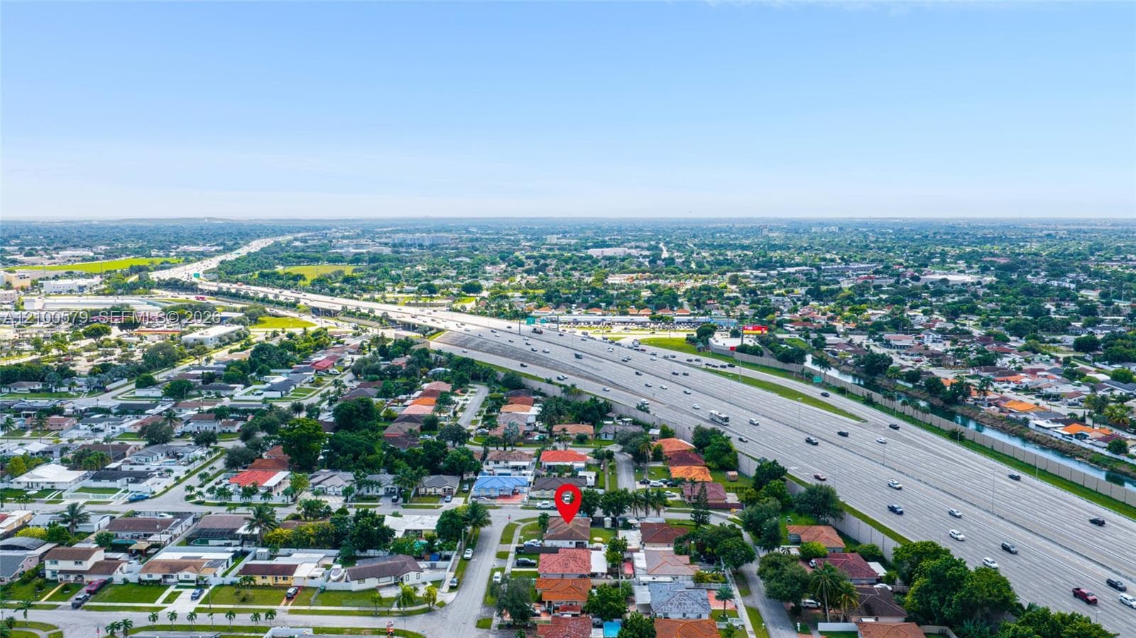 Aerial perspective featuring a residential lot with a multi-gable roofline and paved driveway