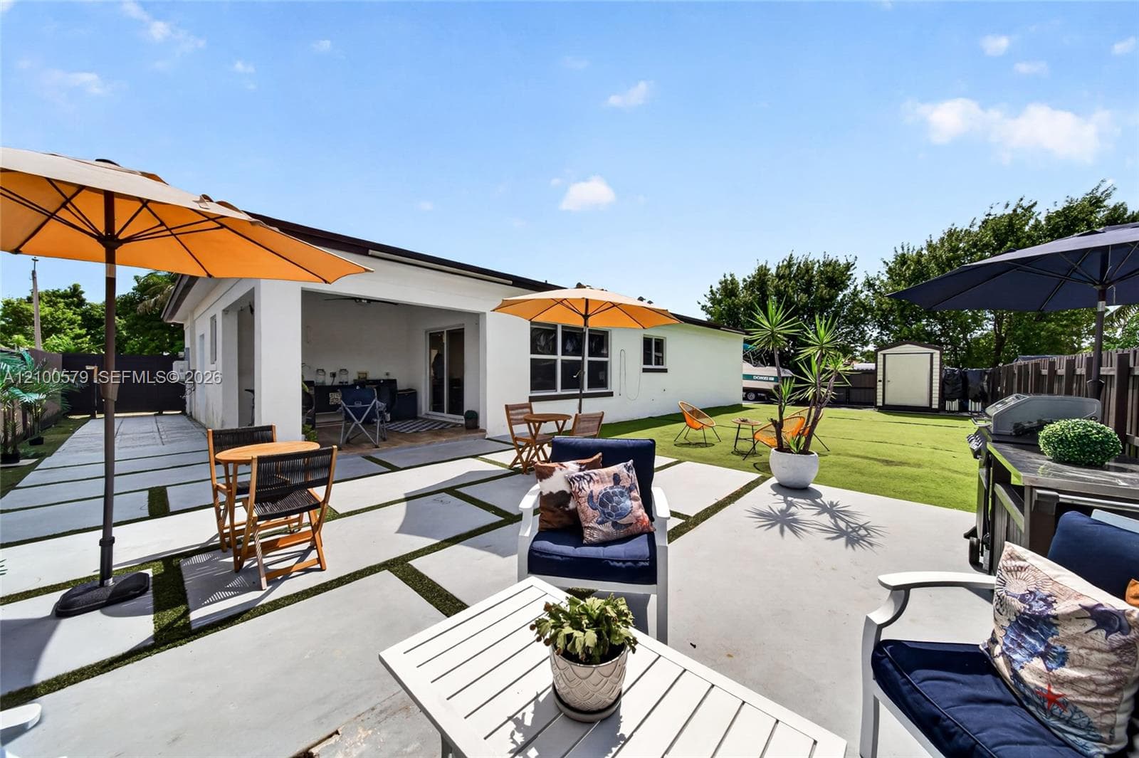 Backyard featuring a concrete paver patio with turf inlays, a covered terrace, and a storage shed