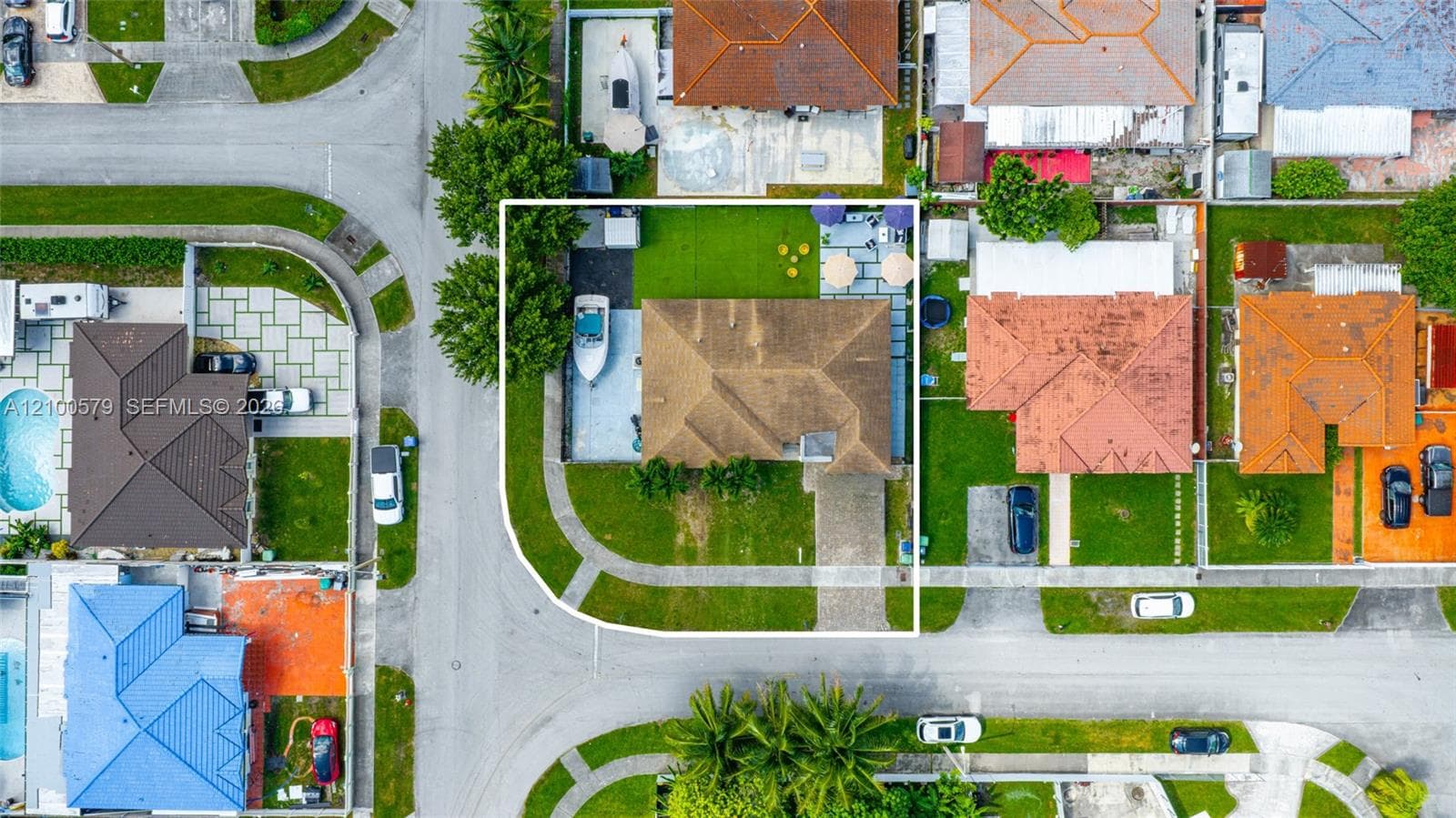 Corner lot residence featuring a paver driveway, side-access parking, a spacious lawn, and a rear hardscaped patio