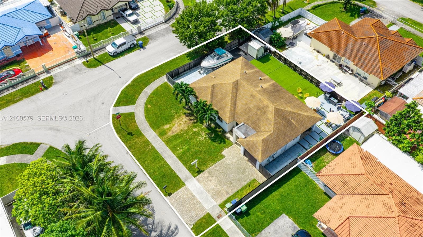 Corner lot residence featuring a multi-hipped roof, concrete paver driveway, fenced backyard, and a side-yard concrete storage area