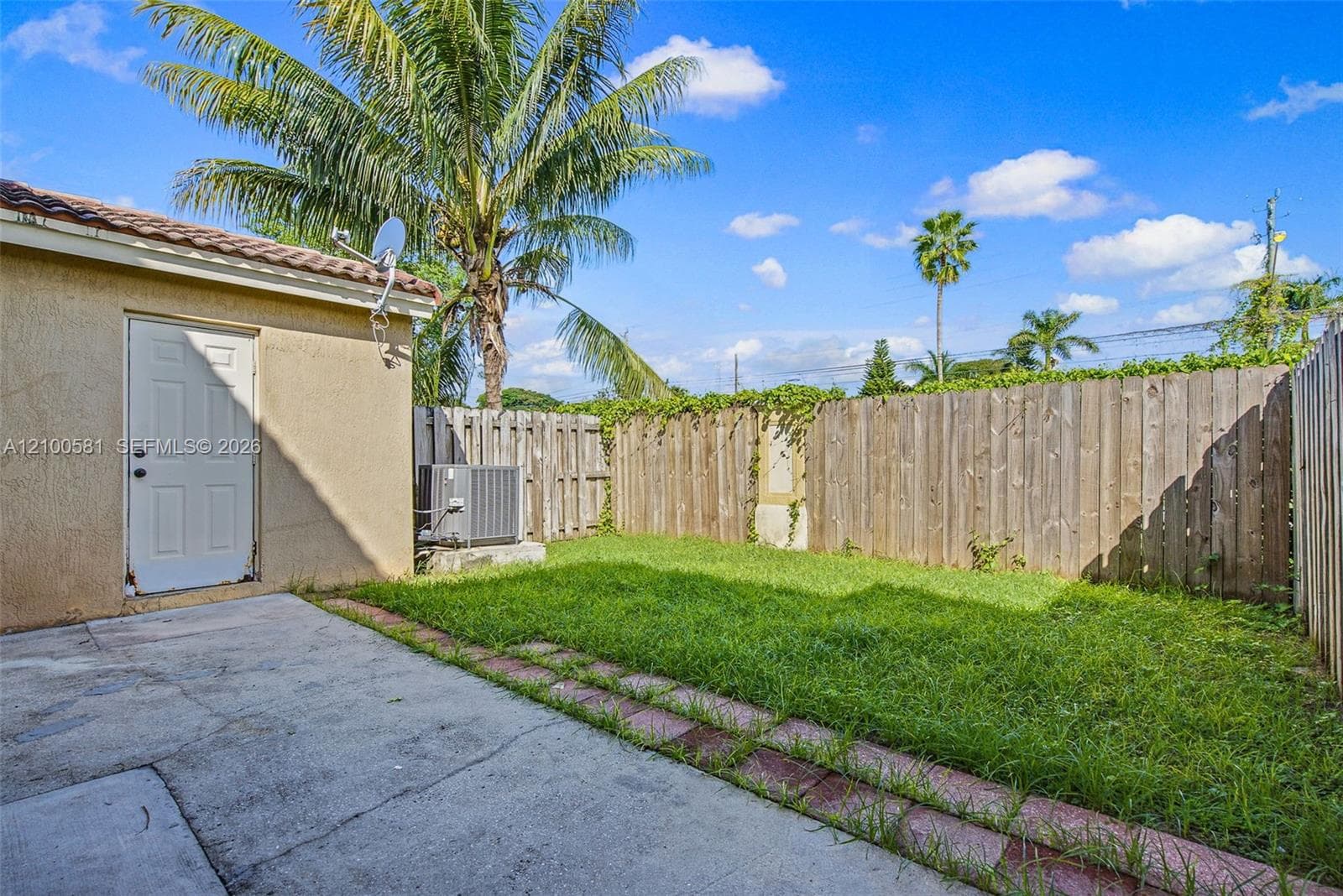 Stucco exterior featuring a concrete patio, sliding glass door, private fenced yard, and a dedicated utility entrance