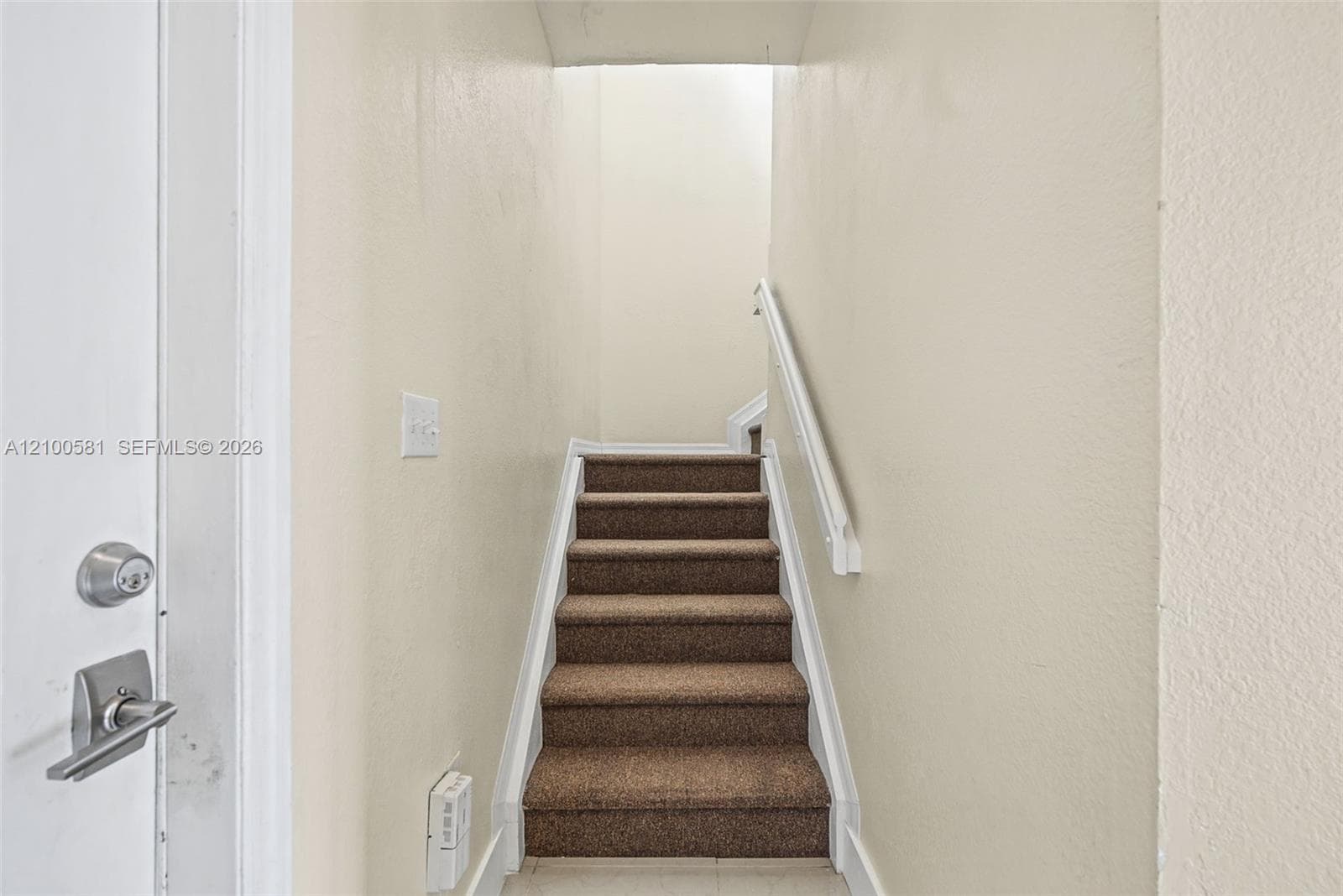 Neutral interior space featuring white spindle railing, closet with bi-fold louvered doors, and wall-to-wall carpeting
