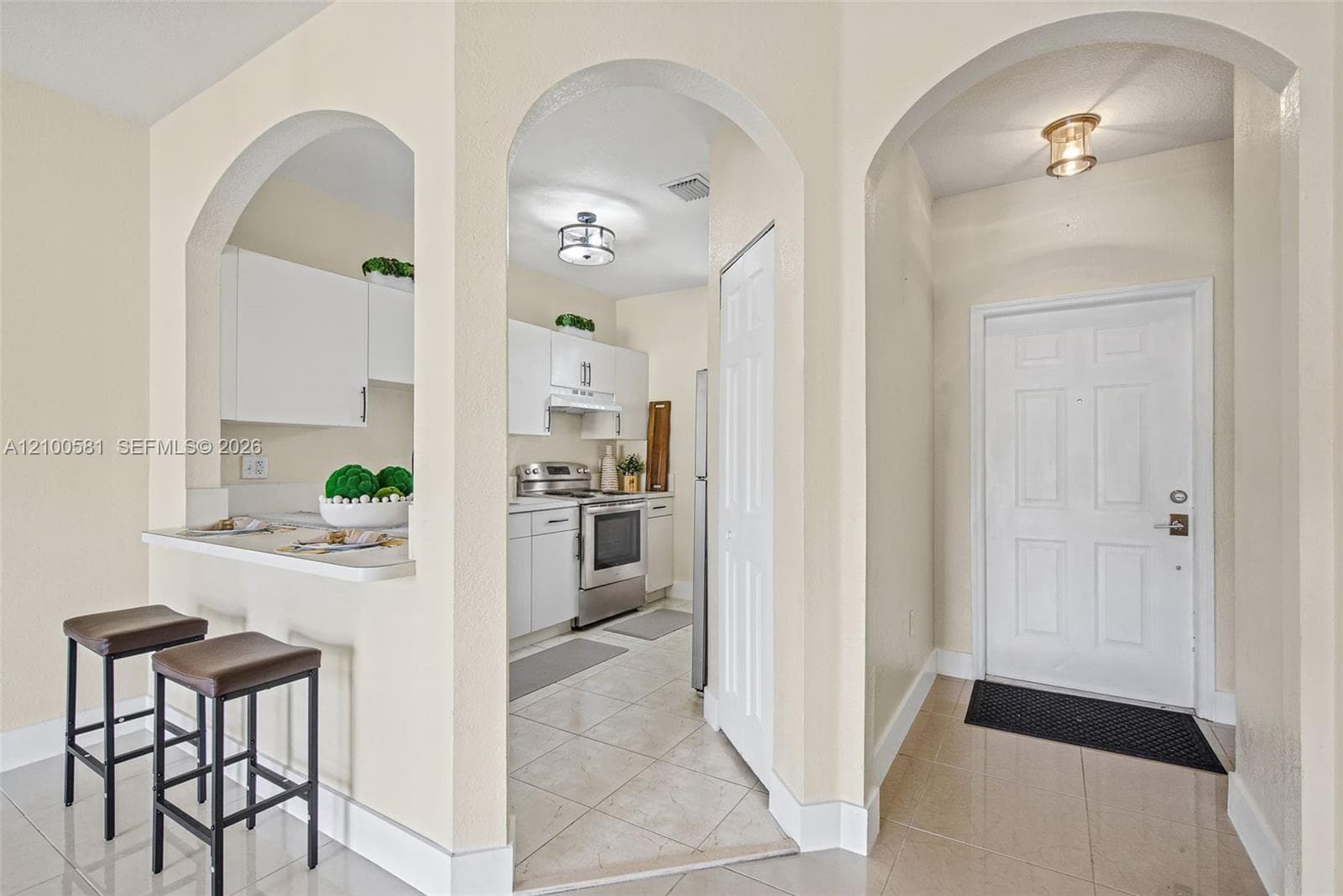 Kitchen featuring white cabinetry with matte black hardware, stainless steel refrigerator and range, dual-basin sink with a matte black faucet, and bifold closet doors