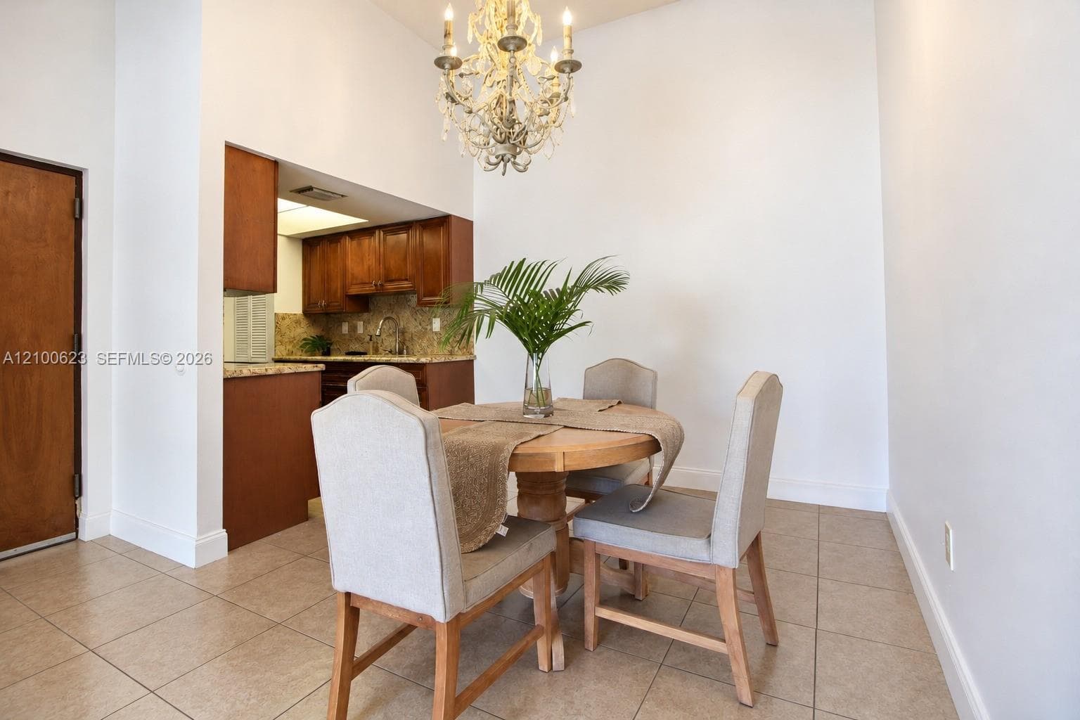 High ceilings featuring an ornate crystal chandelier, tile flooring, and wood cabinetry with stone countertops