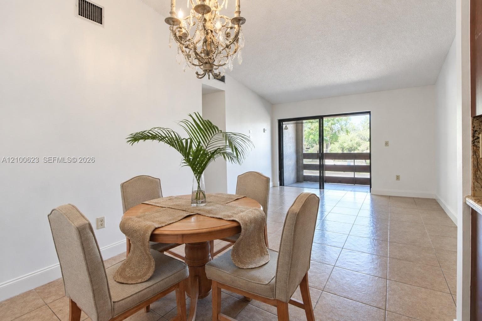Open-concept area featuring tile flooring, a tiered crystal chandelier, and sliding glass doors with exterior access