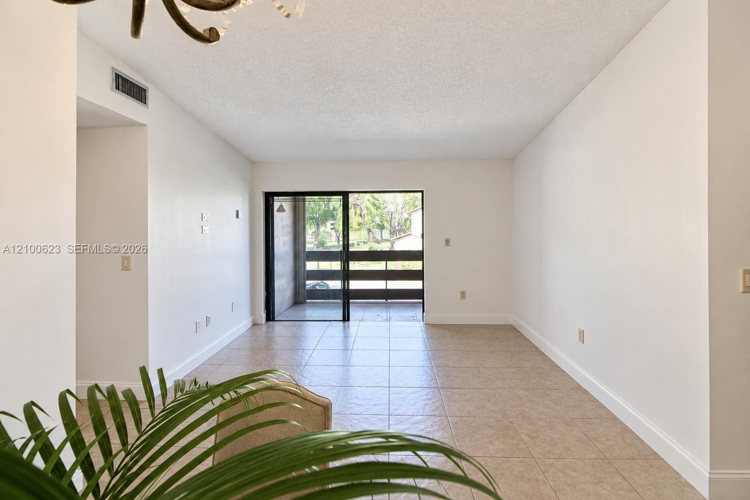 Living area featuring large-format ceramic tile flooring, neutral wall finishes, and sliding glass doors leading to a private balcony