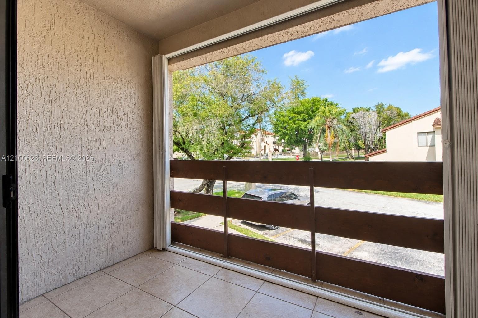 Covered balcony with tiled flooring and a horizontal wood-slat railing