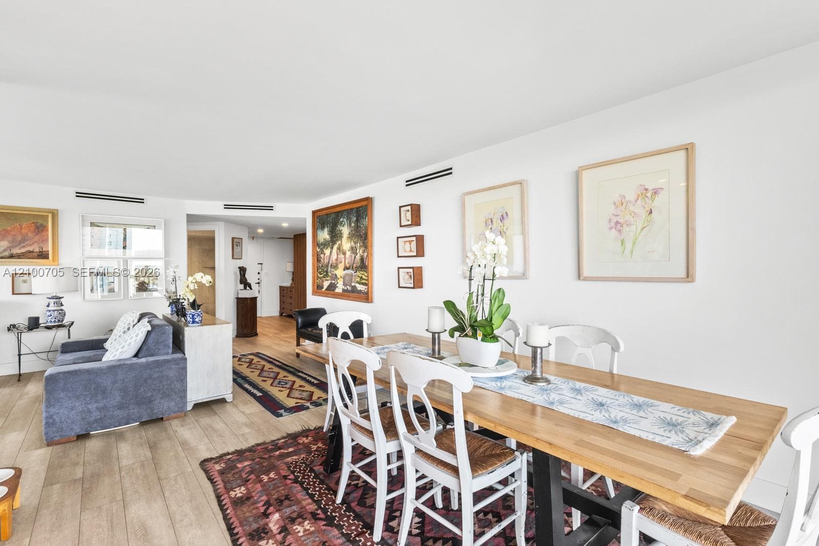 Open-concept living and dining area featuring wood-finish flooring and recessed linear HVAC diffusers