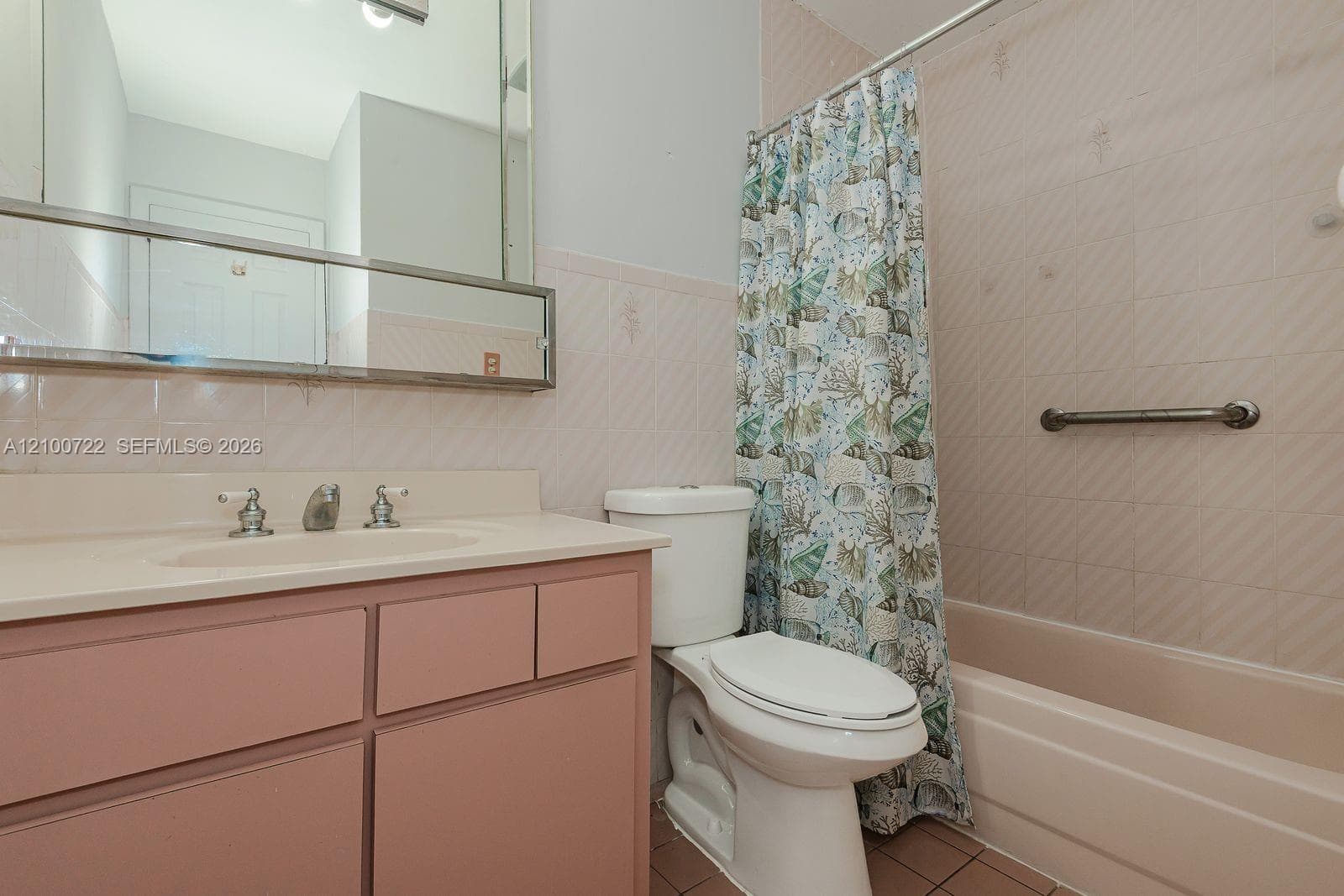 Bathroom featuring a vanity with an integrated basin, a wall-mounted medicine cabinet with a mirror, a tiled shower surround, and a metal grab bar