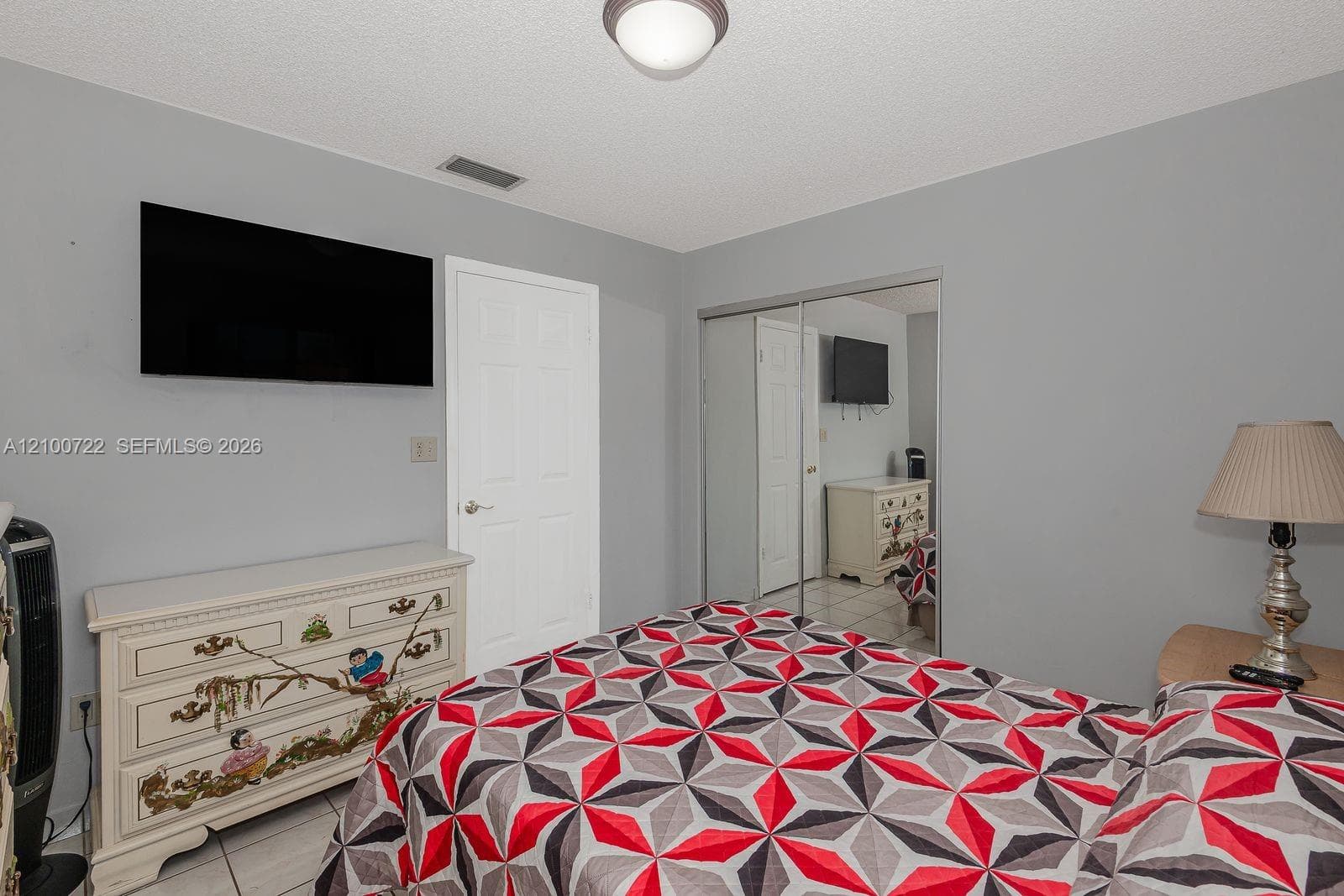 Room featuring neutral interior wall paint, tile flooring, flush-mount ceiling lighting, and mirrored sliding closet doors