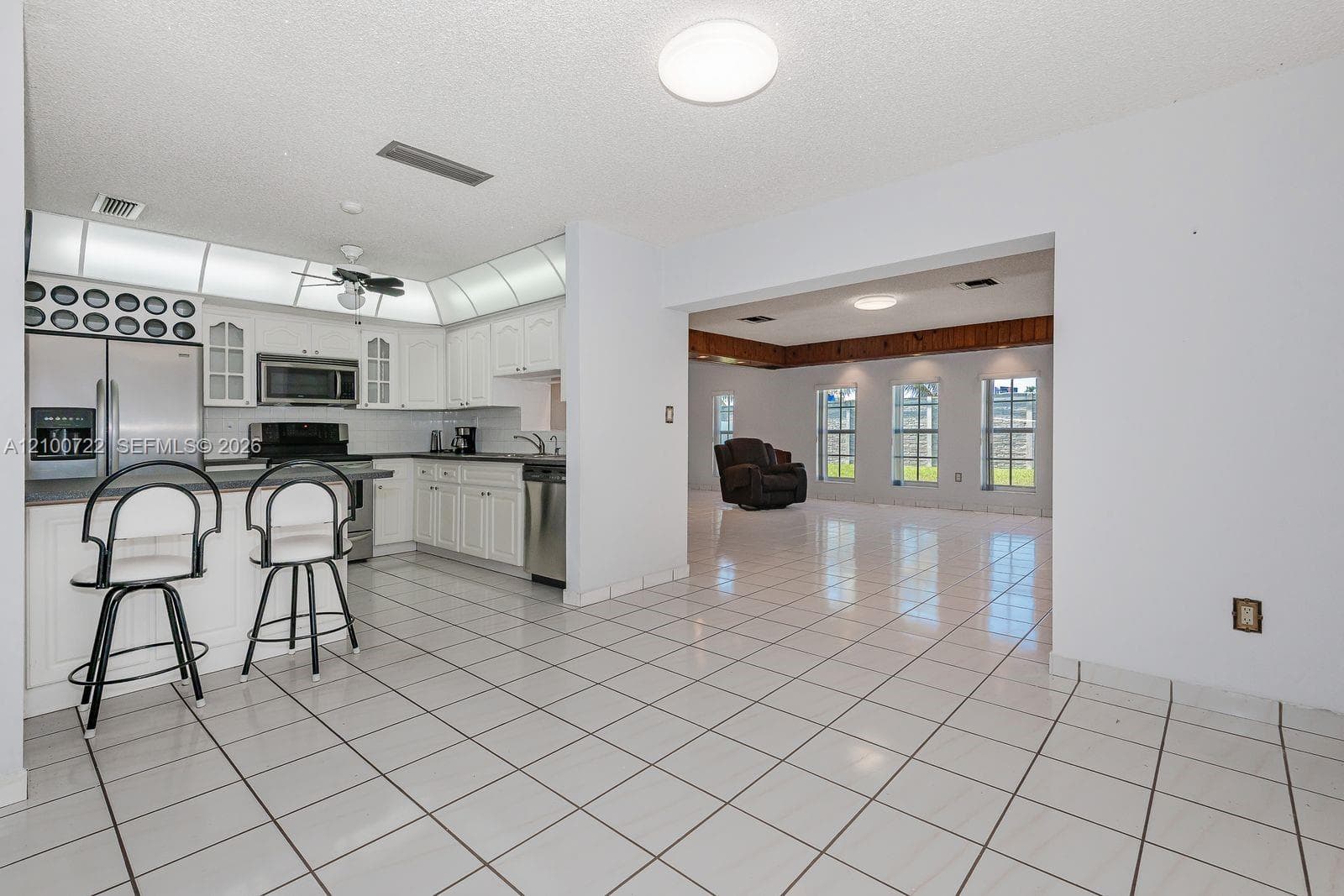 Kitchen featuring white cabinetry, stainless steel appliances, tile flooring, and integrated overhead lighting