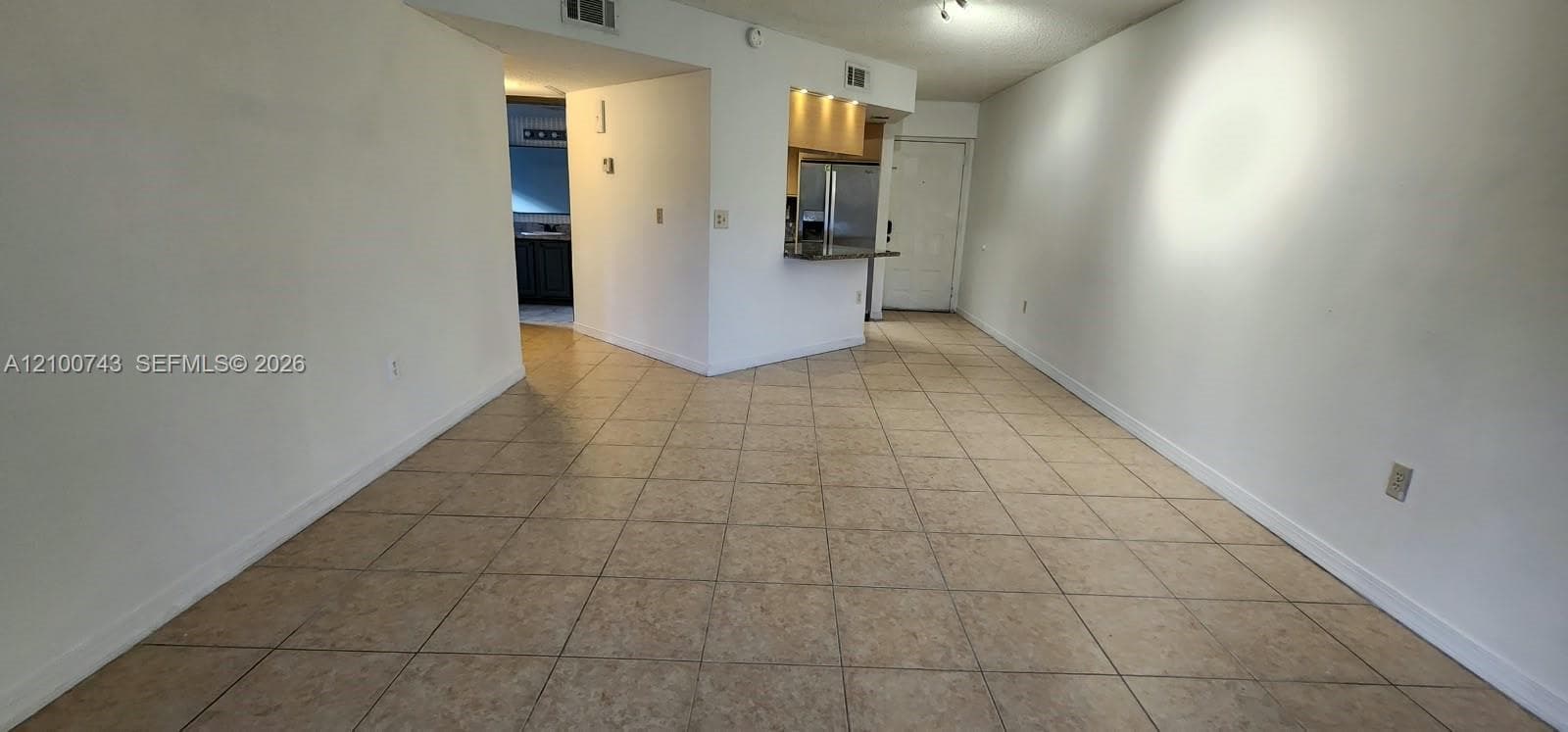 Open living area featuring neutral tile flooring, recessed kitchen lighting, and a breakfast bar