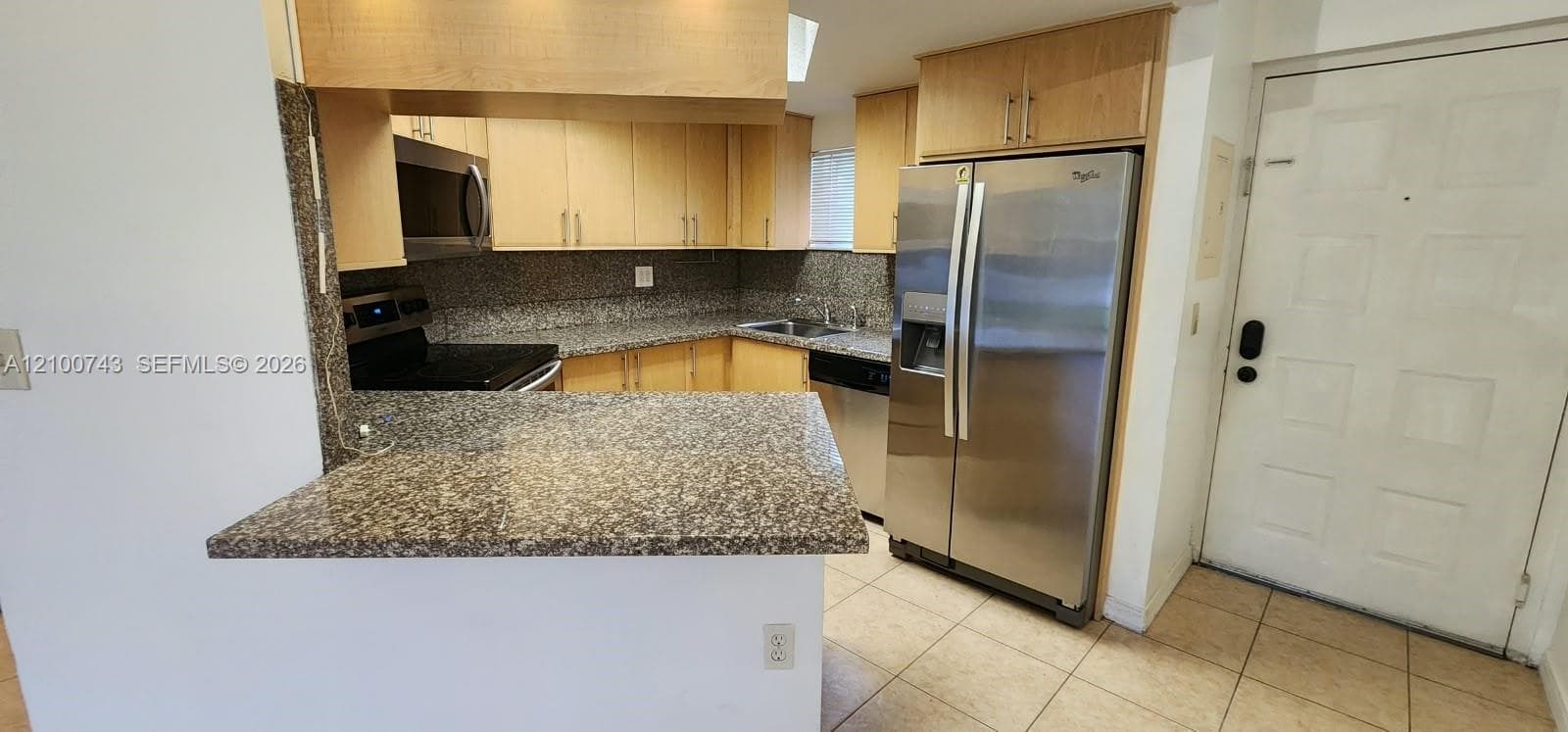 Kitchen featuring light wood cabinetry, stone-surface countertops, stone-tile backsplash, stainless steel appliances, and tile flooring