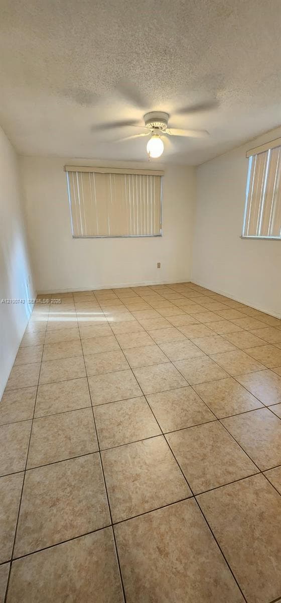 Interior room featuring ceramic tile flooring, neutral wall finishes, a central ceiling fan with integrated lighting, and vertical window blinds